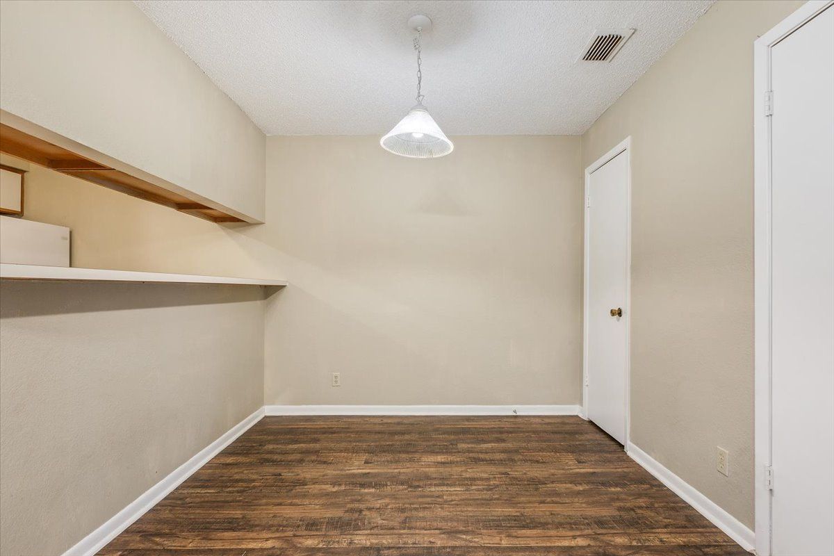 An empty room with hardwood floors and a ceiling light.