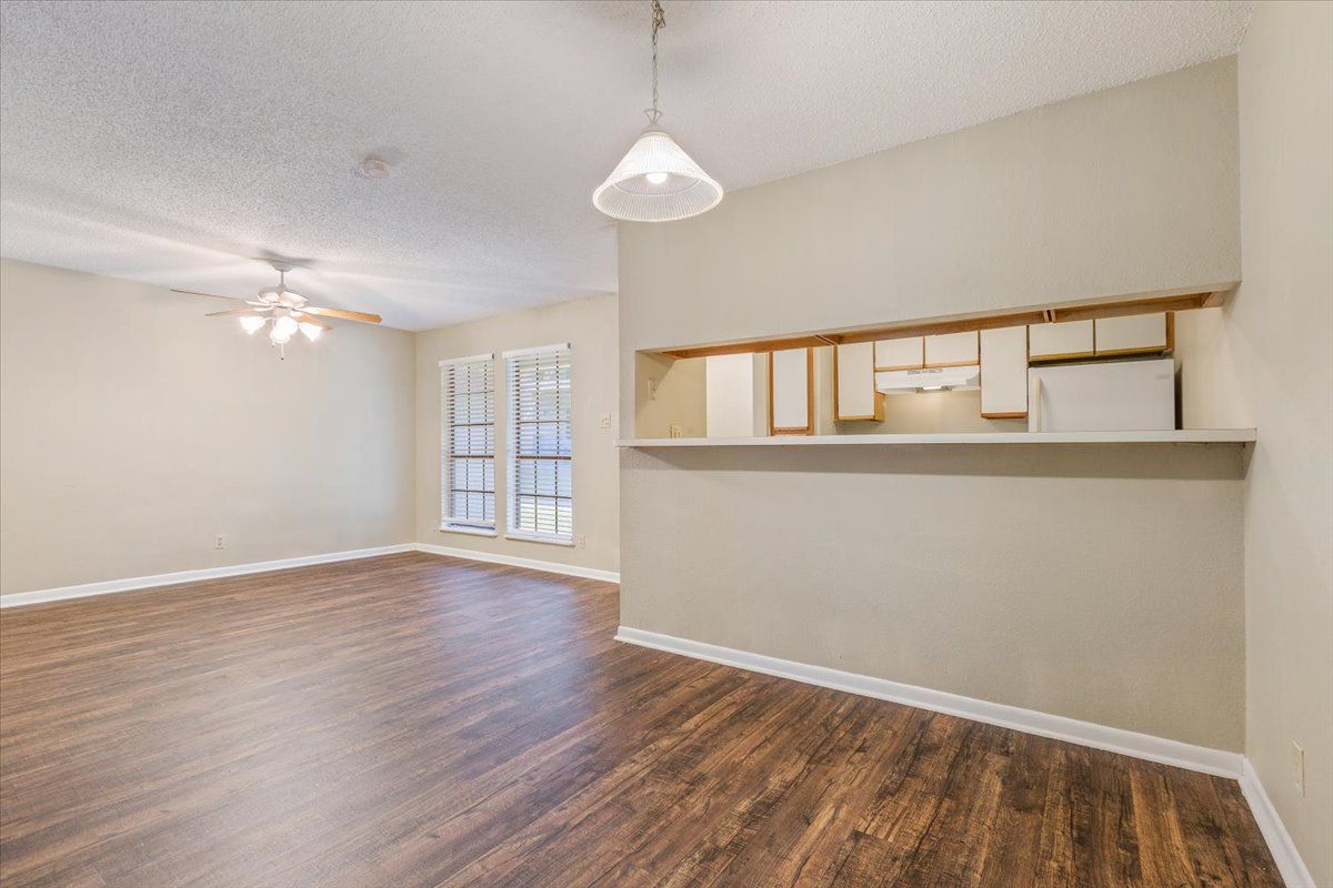 An empty living room with hardwood floors and a ceiling fan.
