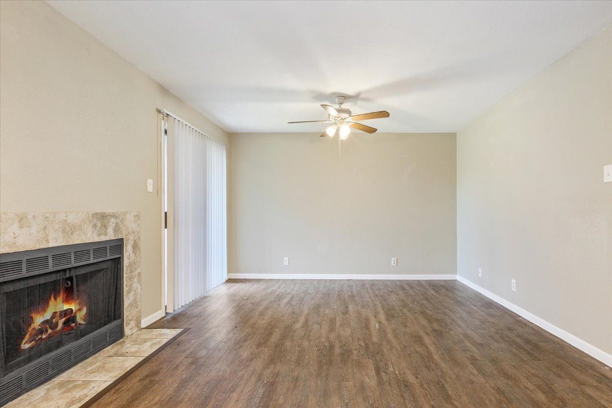 An empty living room with a fireplace and a ceiling fan.