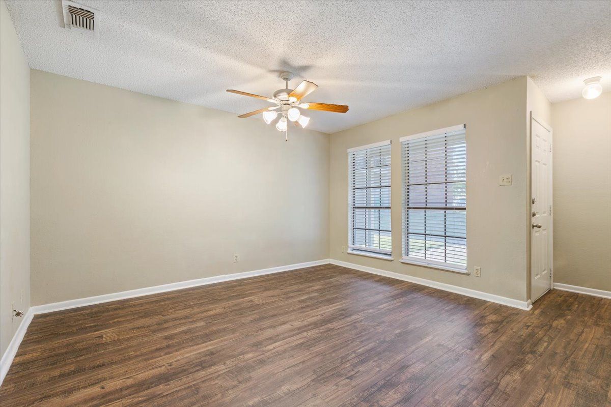 An empty living room with hardwood floors and a ceiling fan.