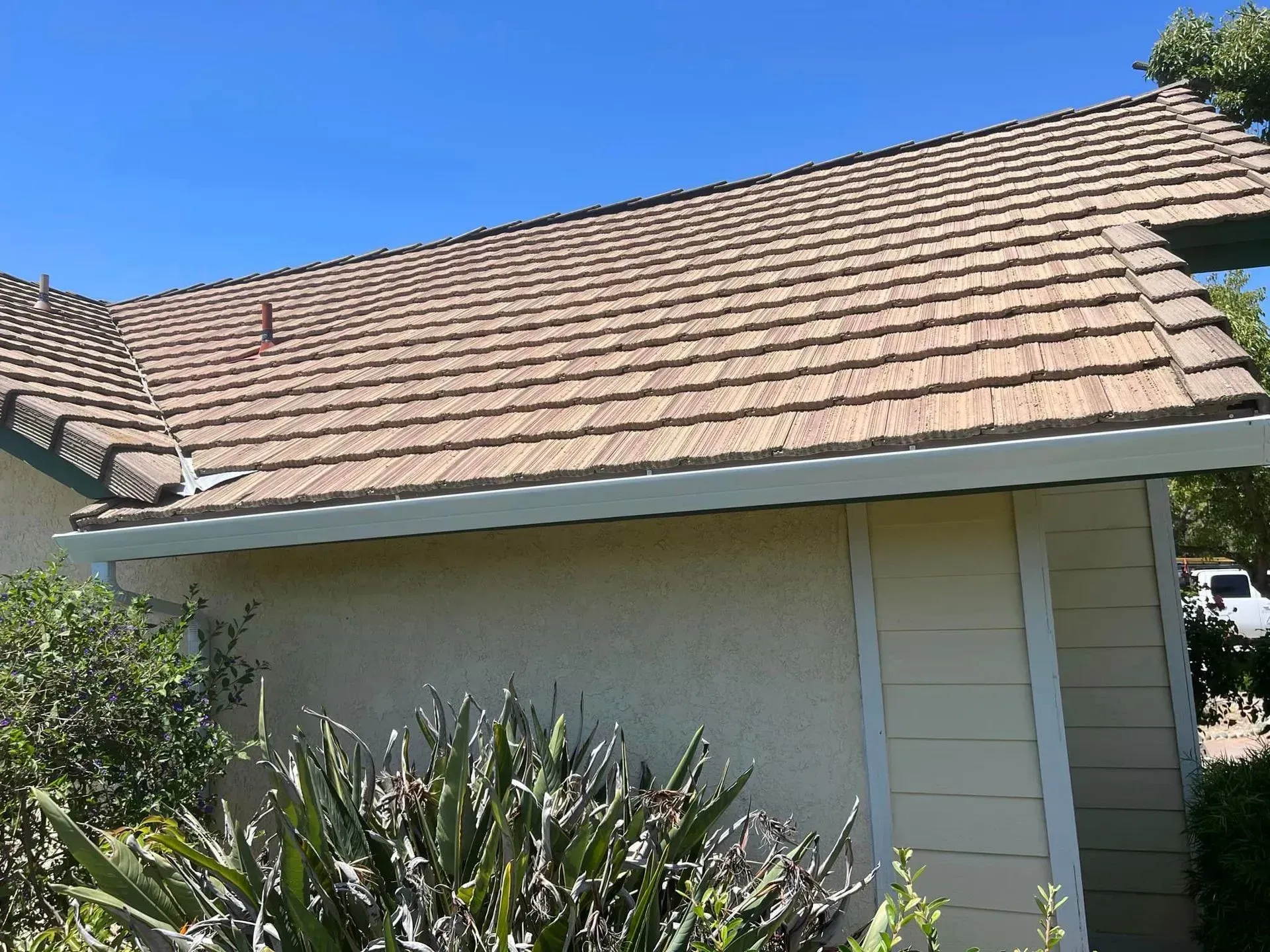 A house with a brown roof and a blue sky in the background.
