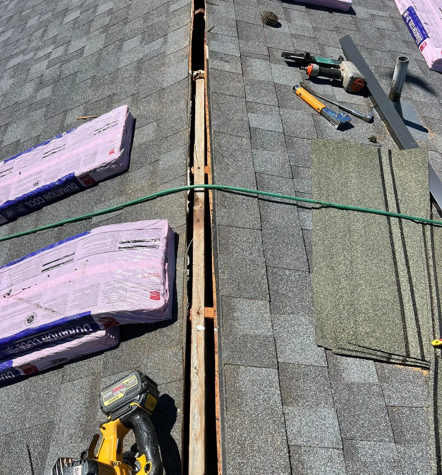 A roof with a hole in it and tools on it.