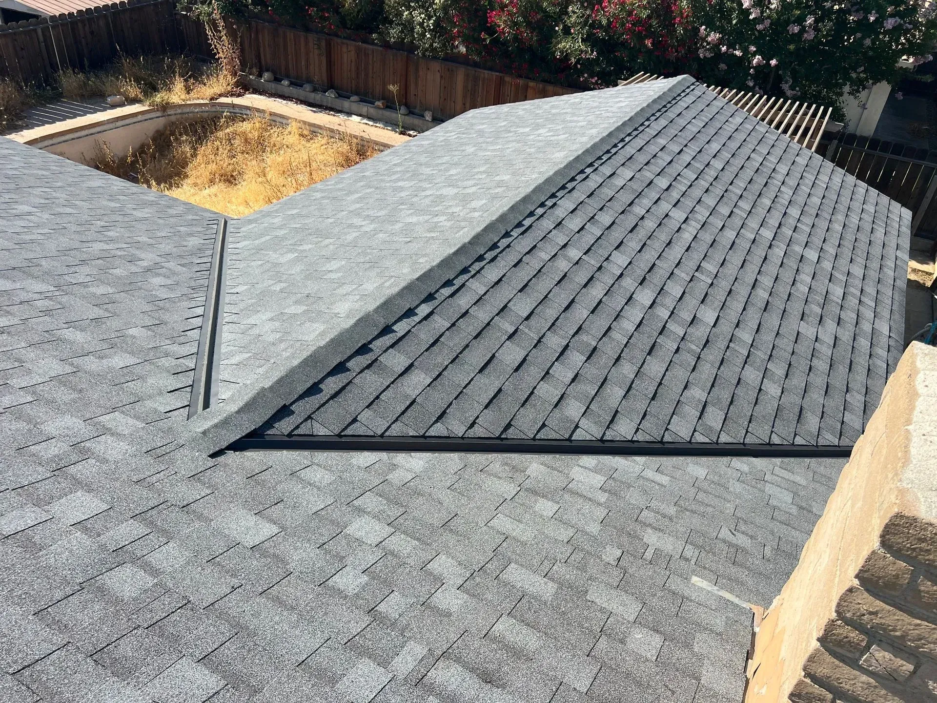 A roof of a house with a pool in the background.