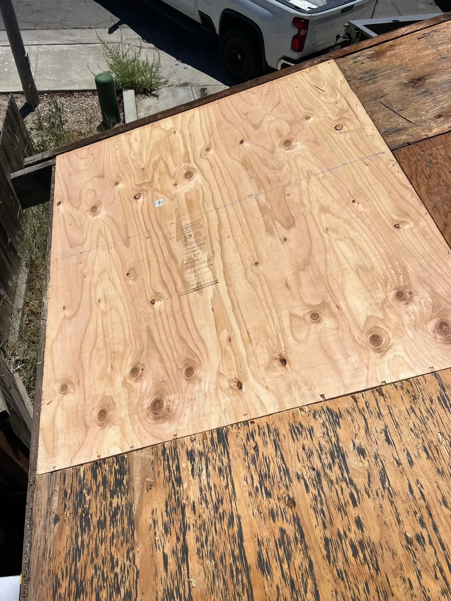 A piece of plywood is sitting on top of a roof next to a truck.