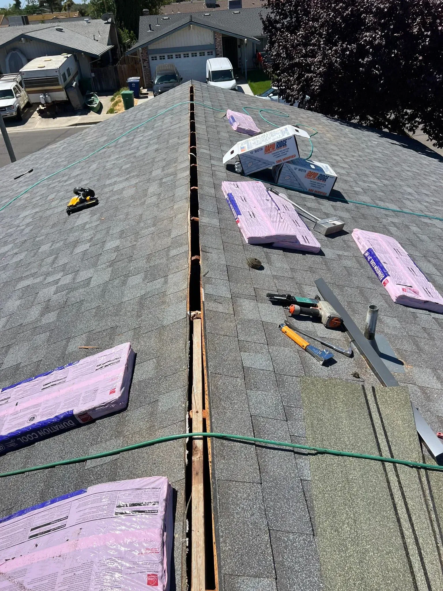 The roof of a house is being repaired and there is a truck in the background.