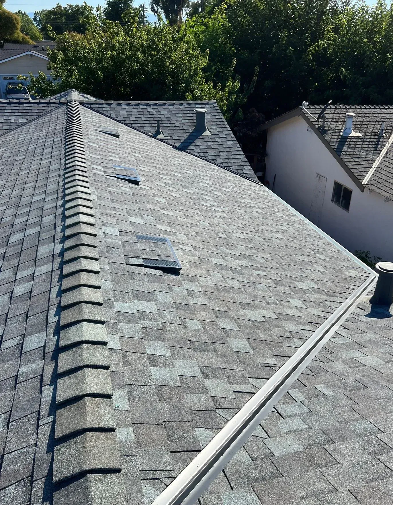 A close up of a roof with a white house in the background.