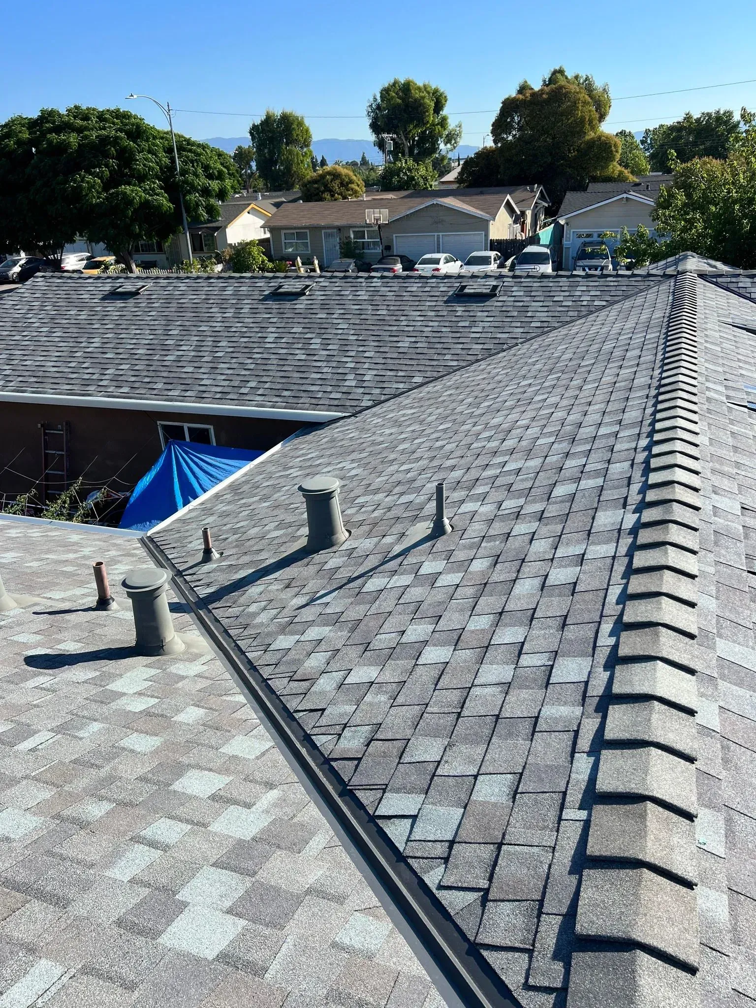 The roof of a house with a blue tarp on it.
