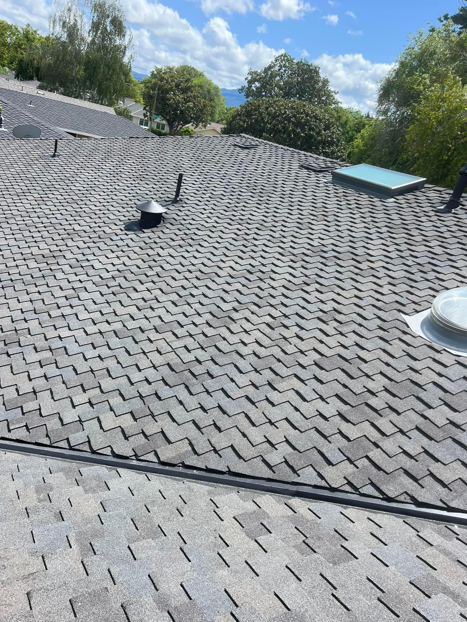A roof with a lot of shingles and a skylight on it.
