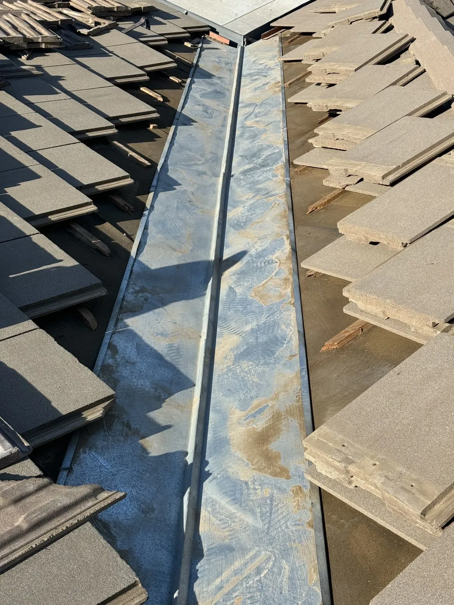 A close up of a roof with shingles and a metal gutter.