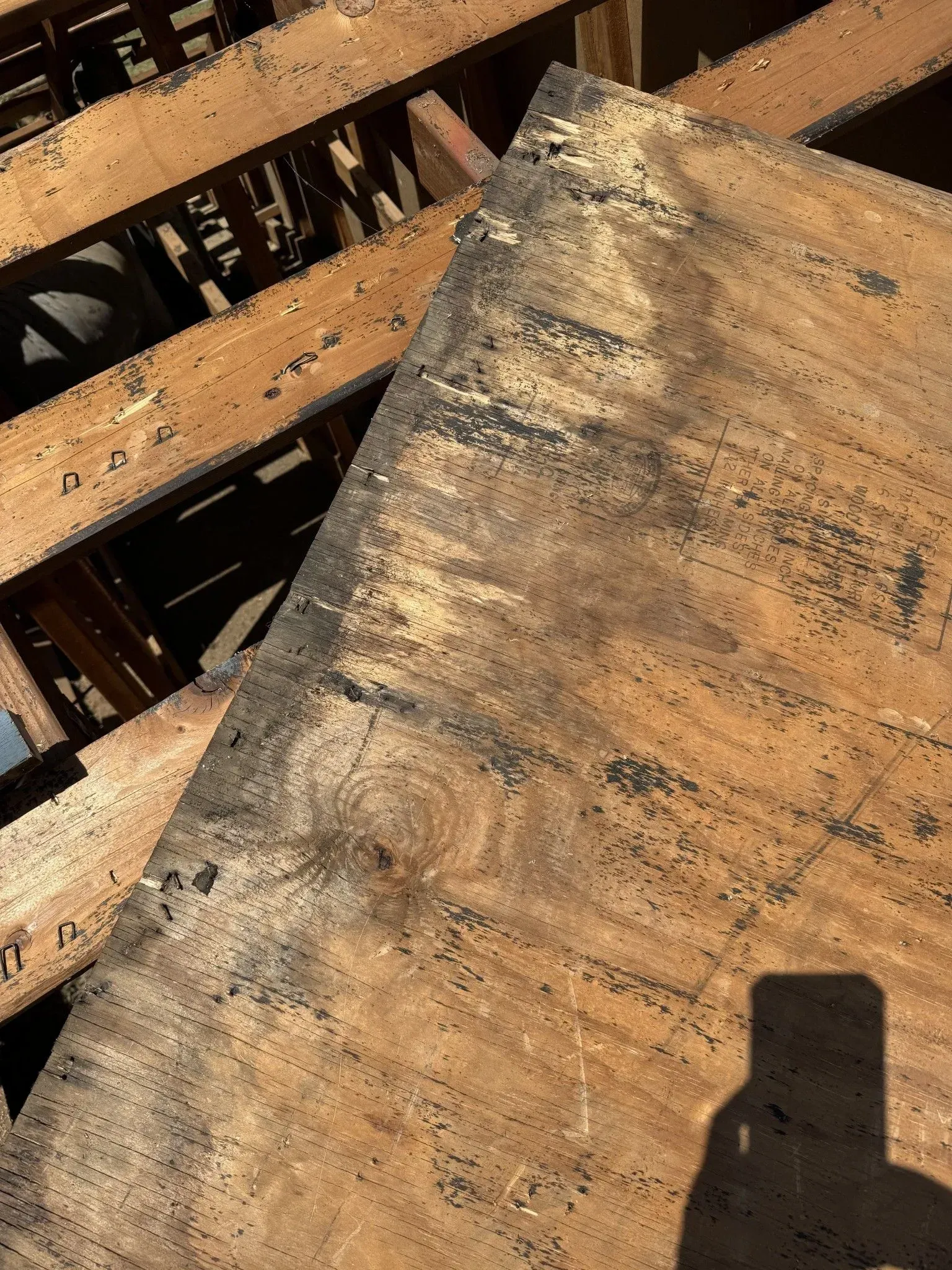 A piece of wood is sitting on top of a pile of wooden pallets.