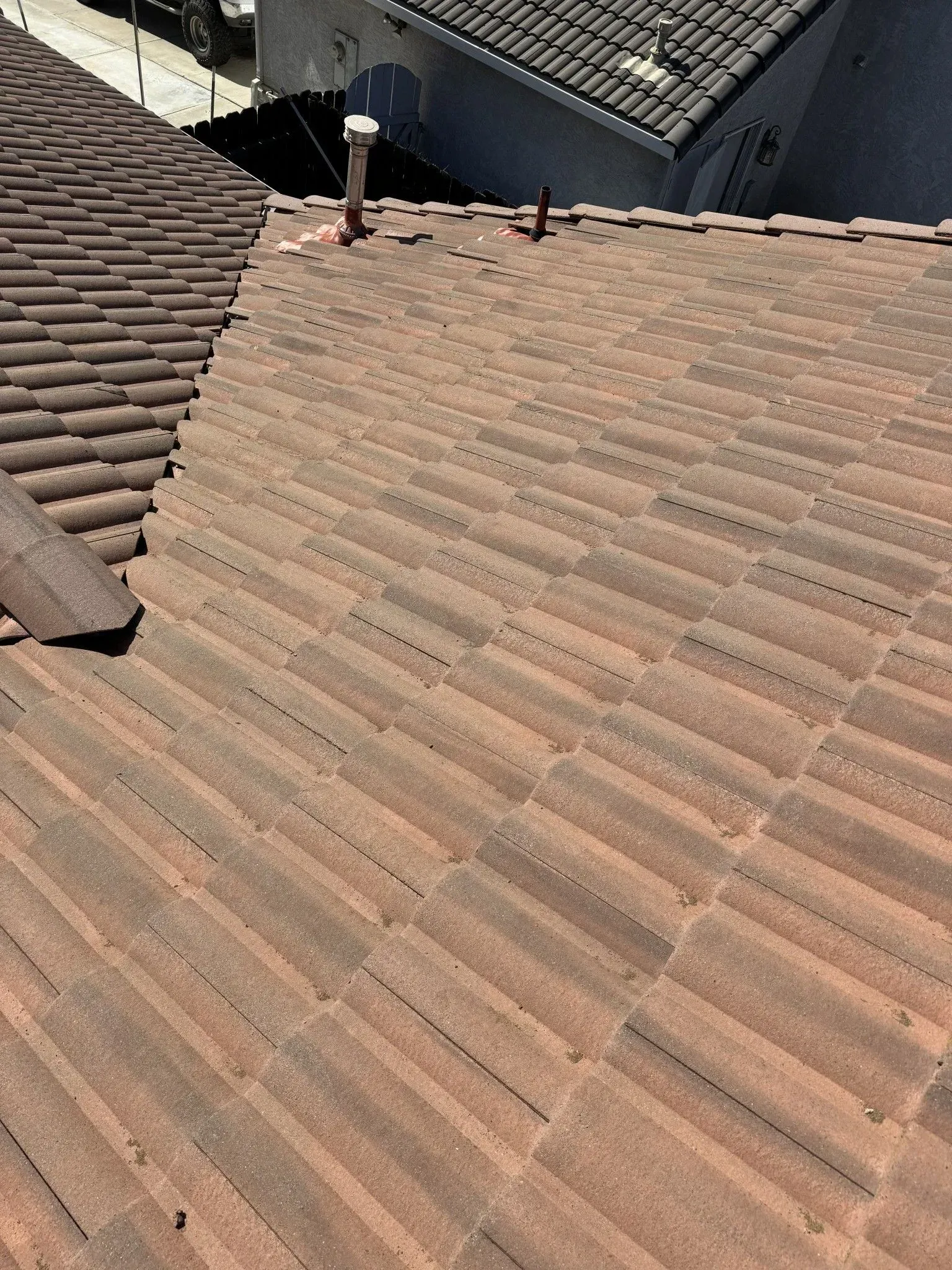 A close up of a tiled roof with a chimney on top of it.
