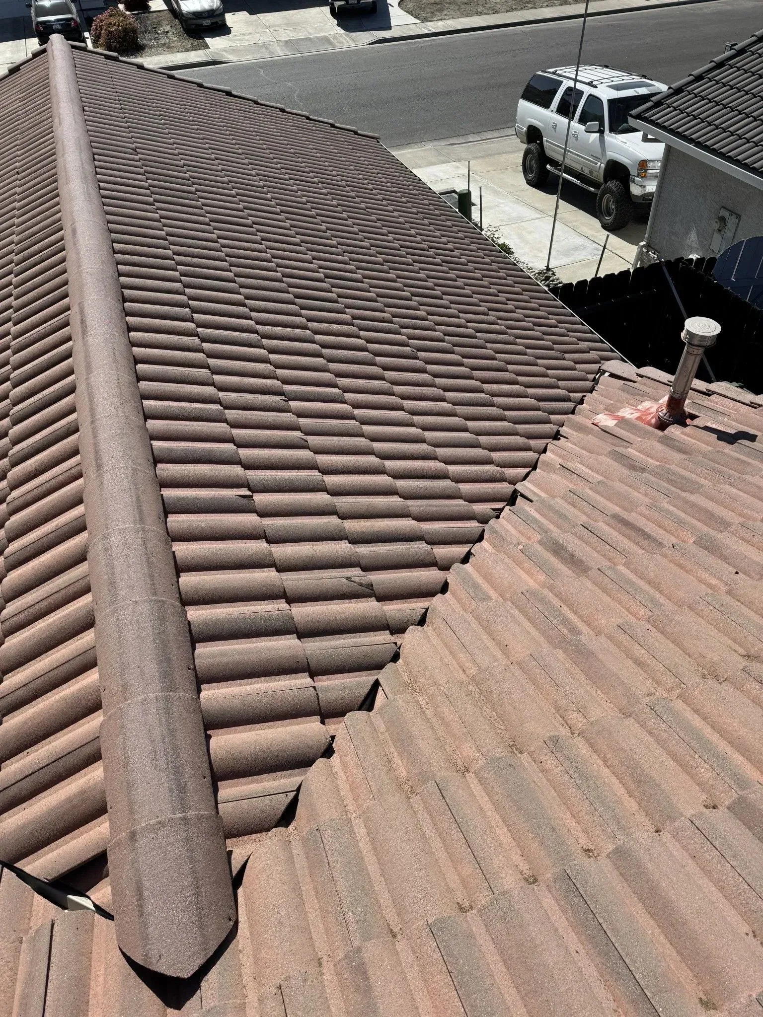 A close up of a tiled roof with a truck parked in the background.