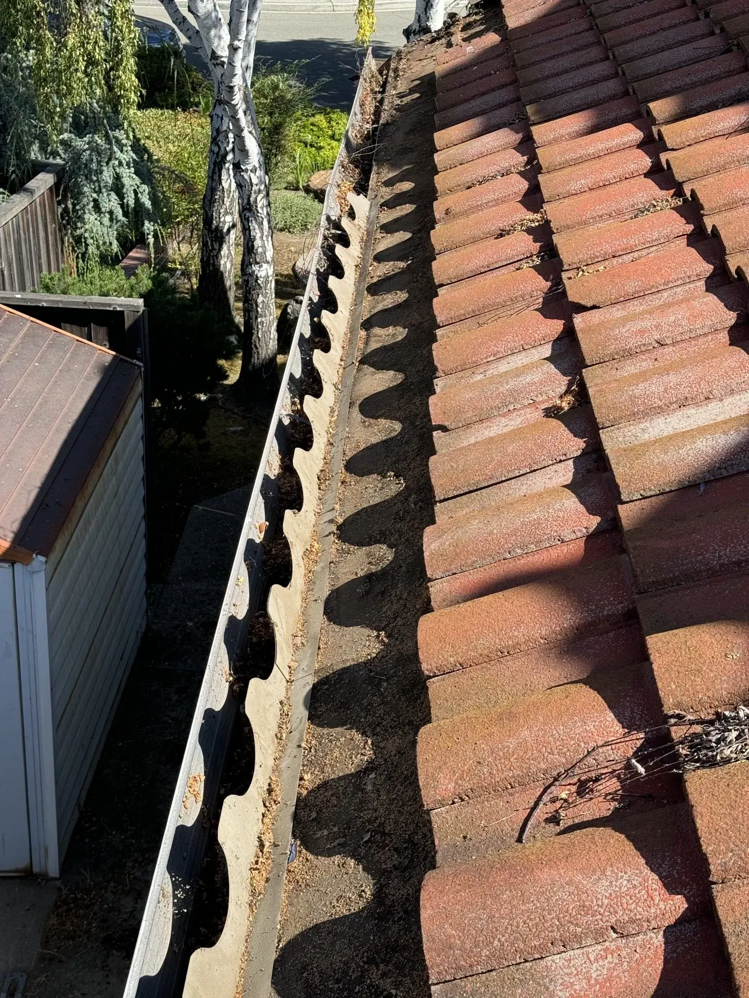 A close up of a gutter on a tiled roof.