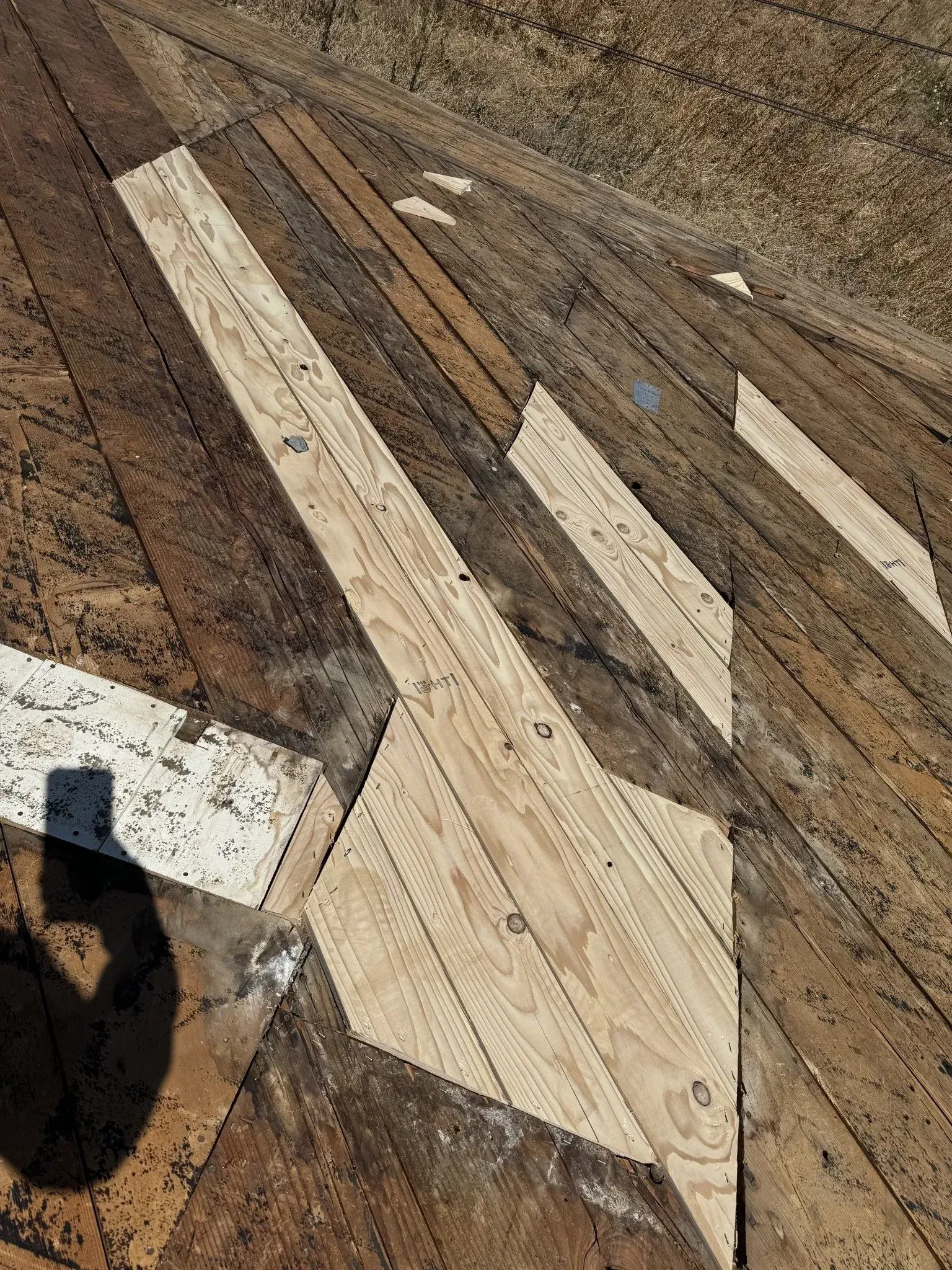 A shadow of a person is cast on a wooden floor.