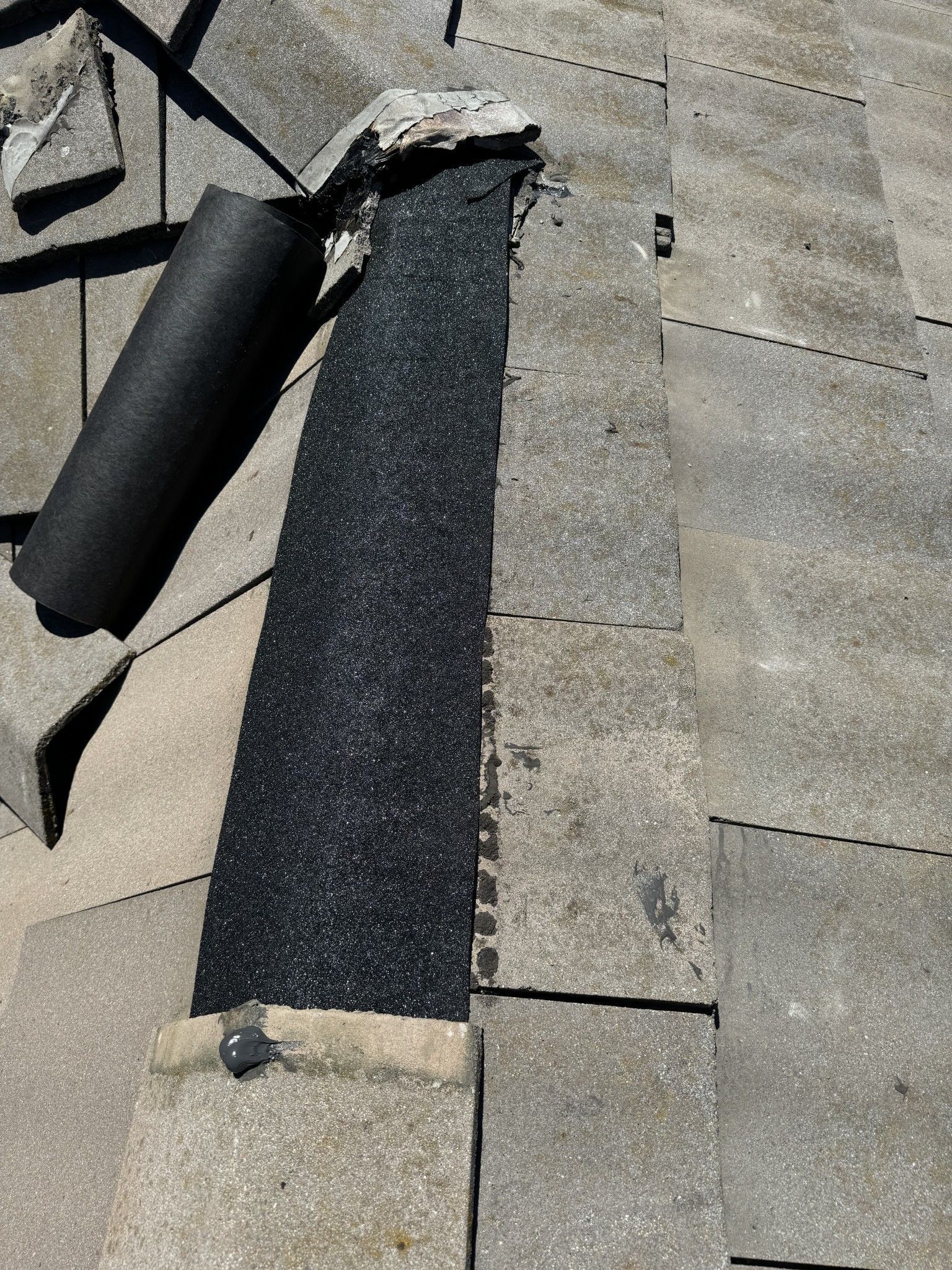 A roll of black rubber is sitting on top of a concrete surface.