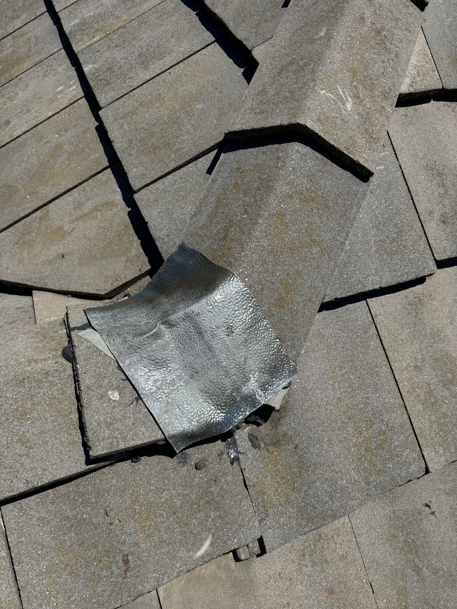 A piece of aluminum foil is laying on top of a concrete floor.