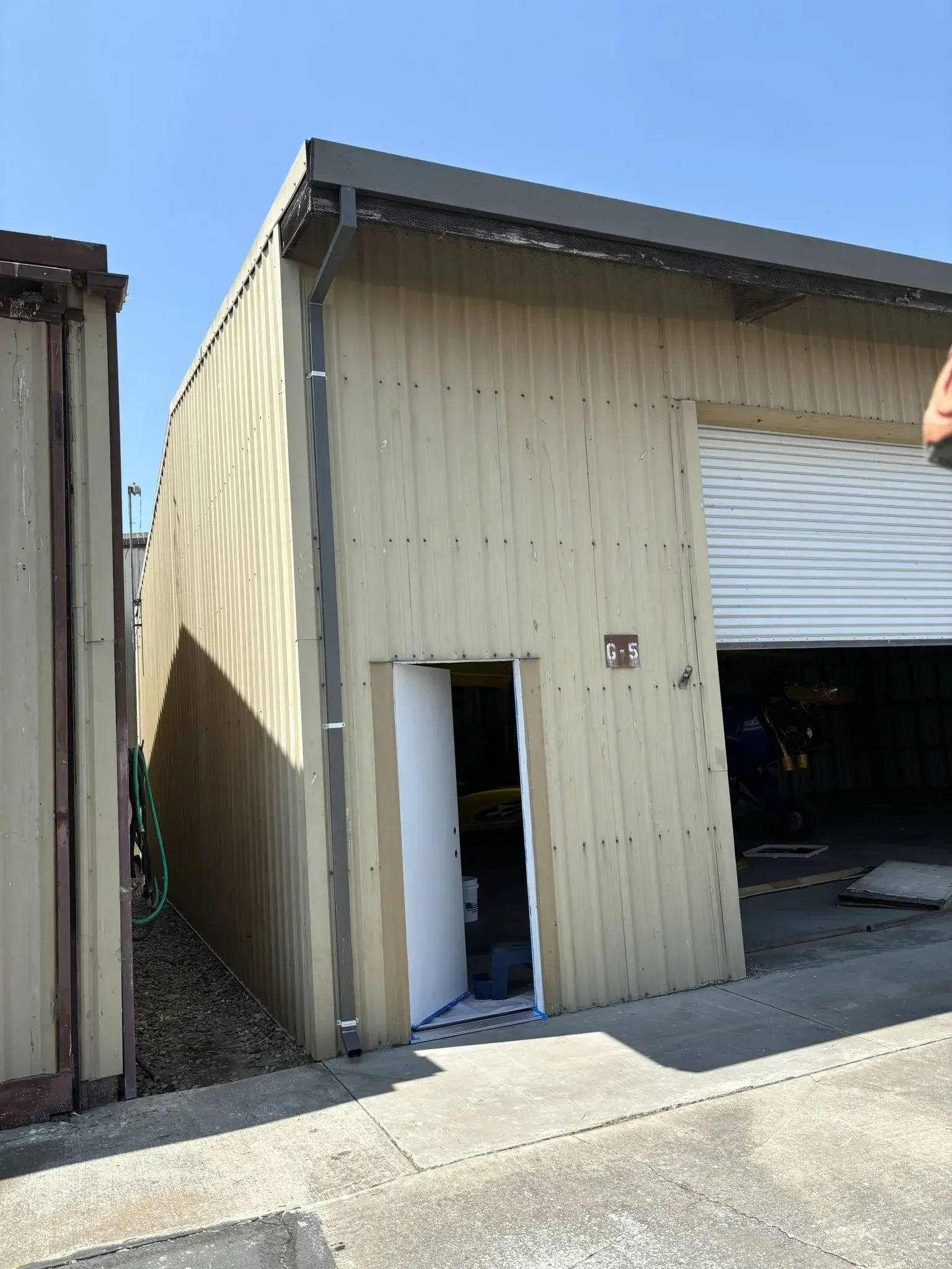 A large wooden building with a white door and a garage door.