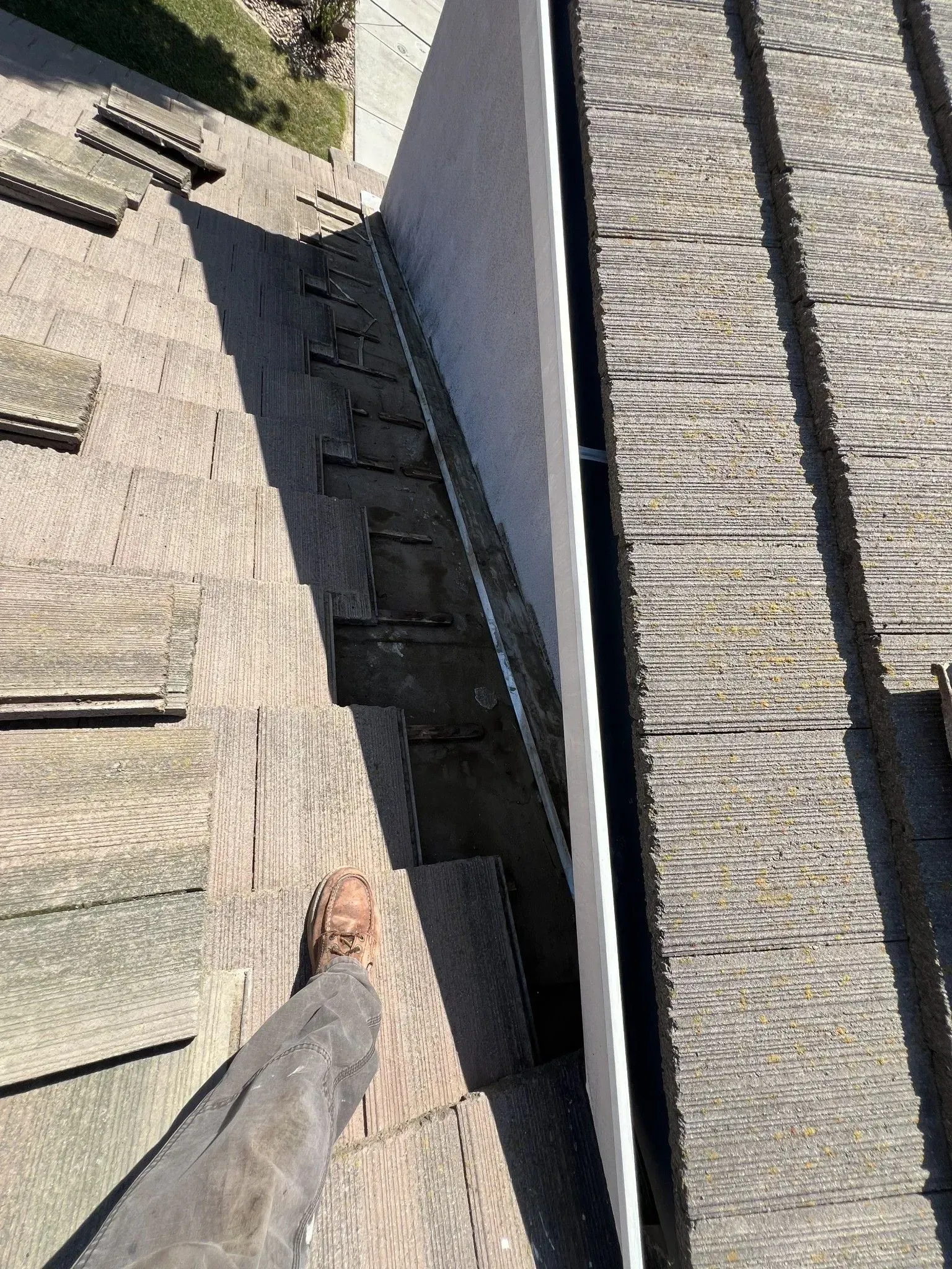 A person is standing on a roof next to a gutter.