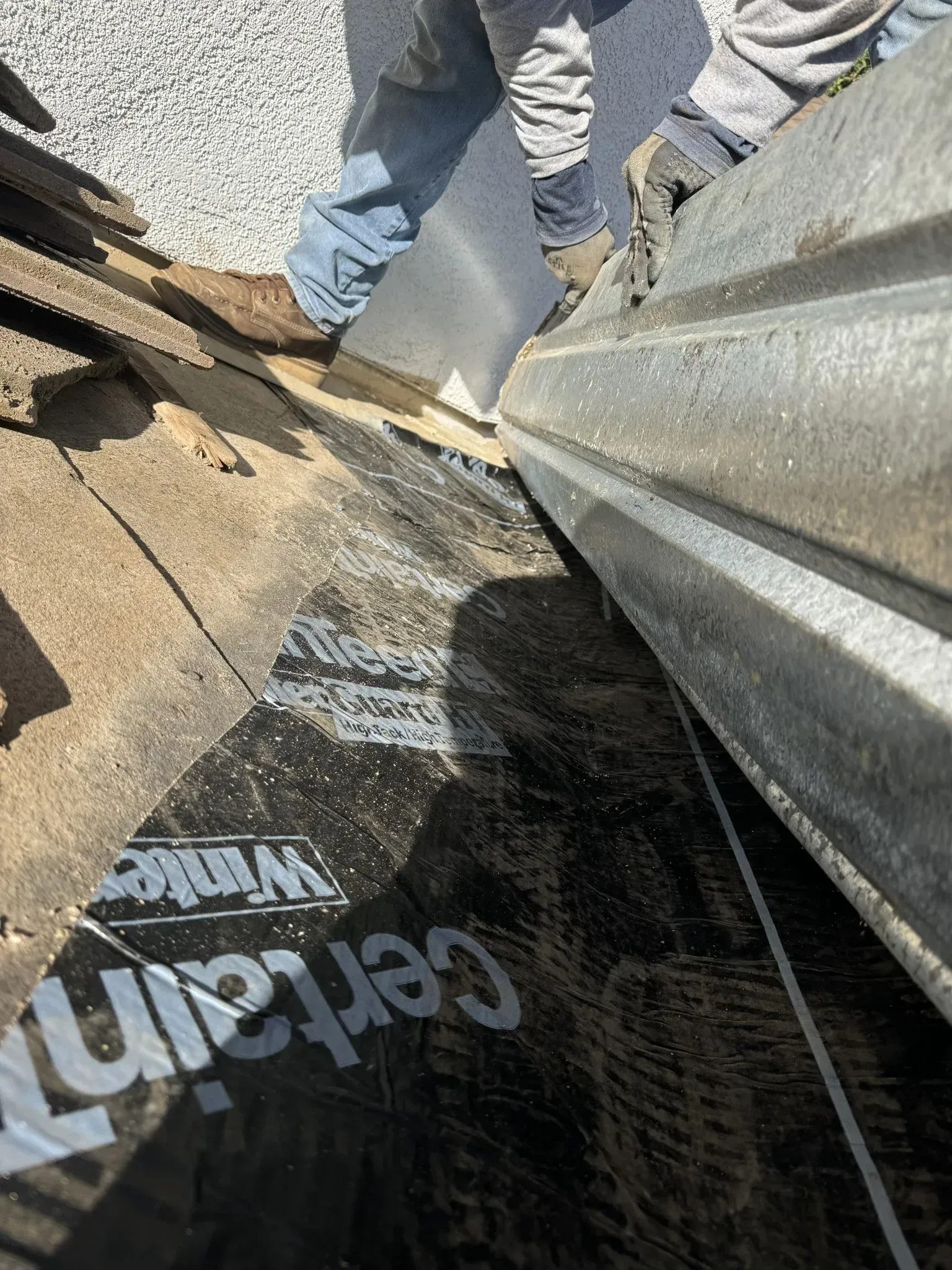 A person is working on a roof with a tool.
