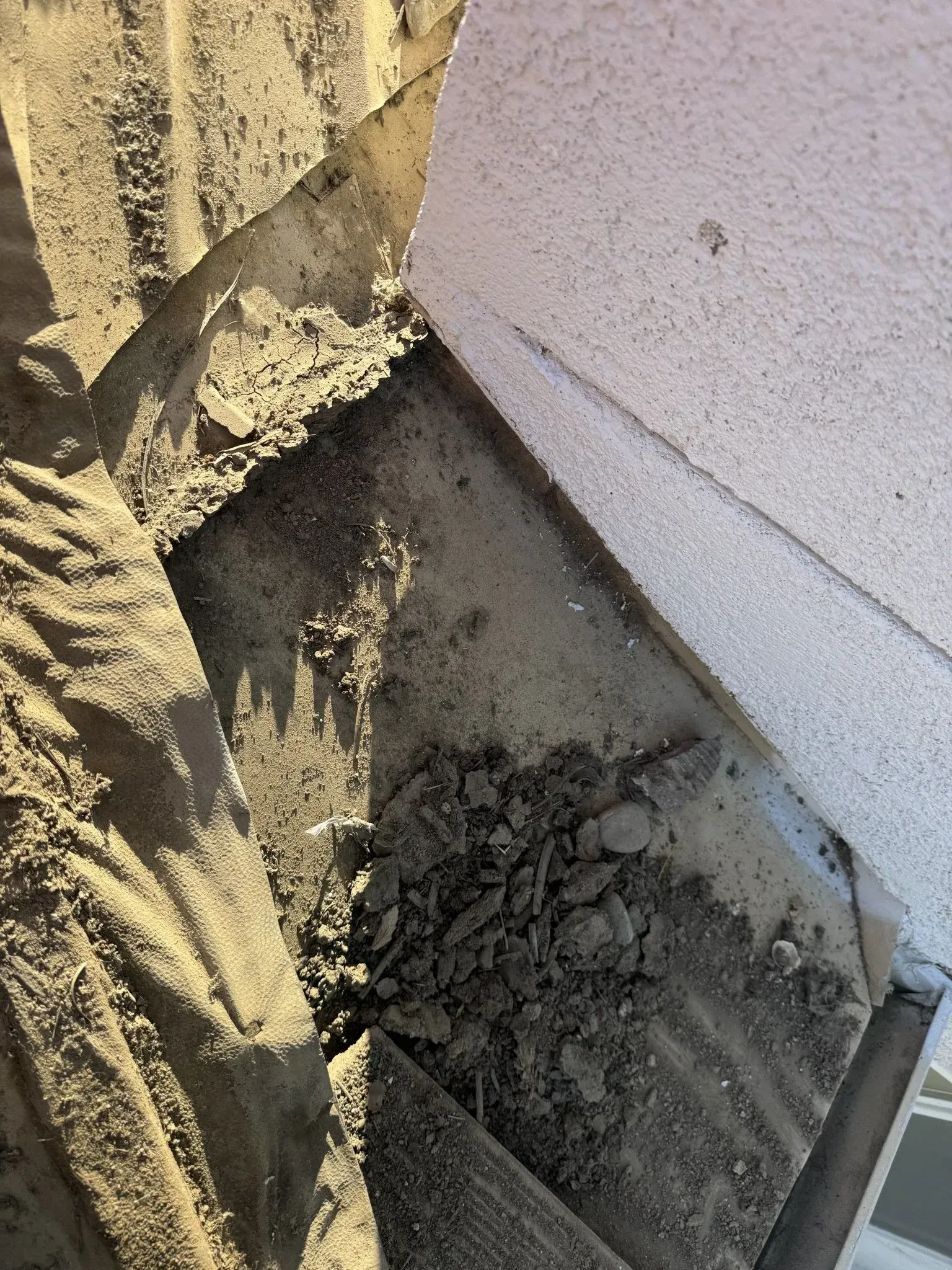 A pile of dirt is sitting on top of a white wall.