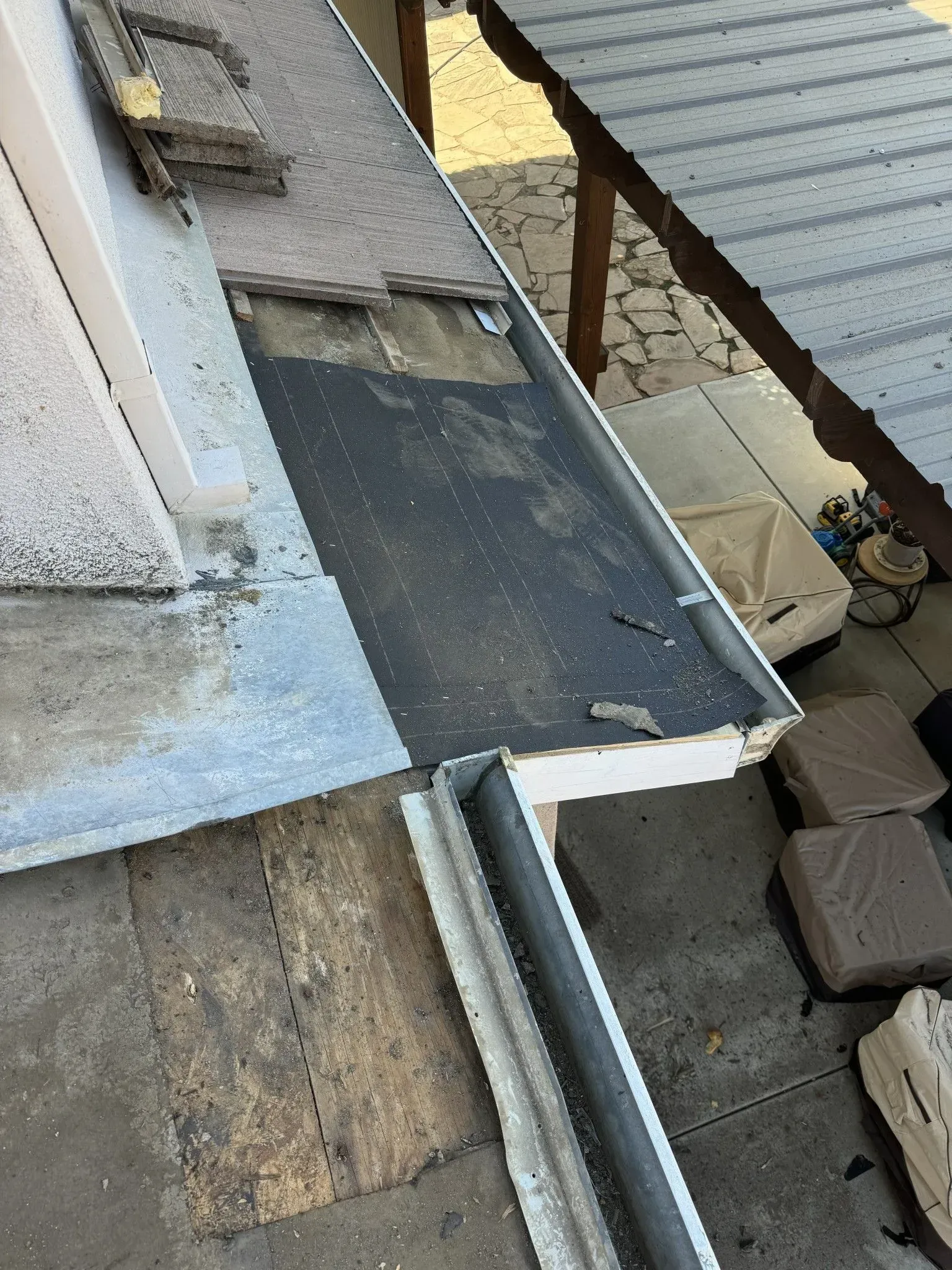 A close up of a gutter on a roof with a roof in the background.
