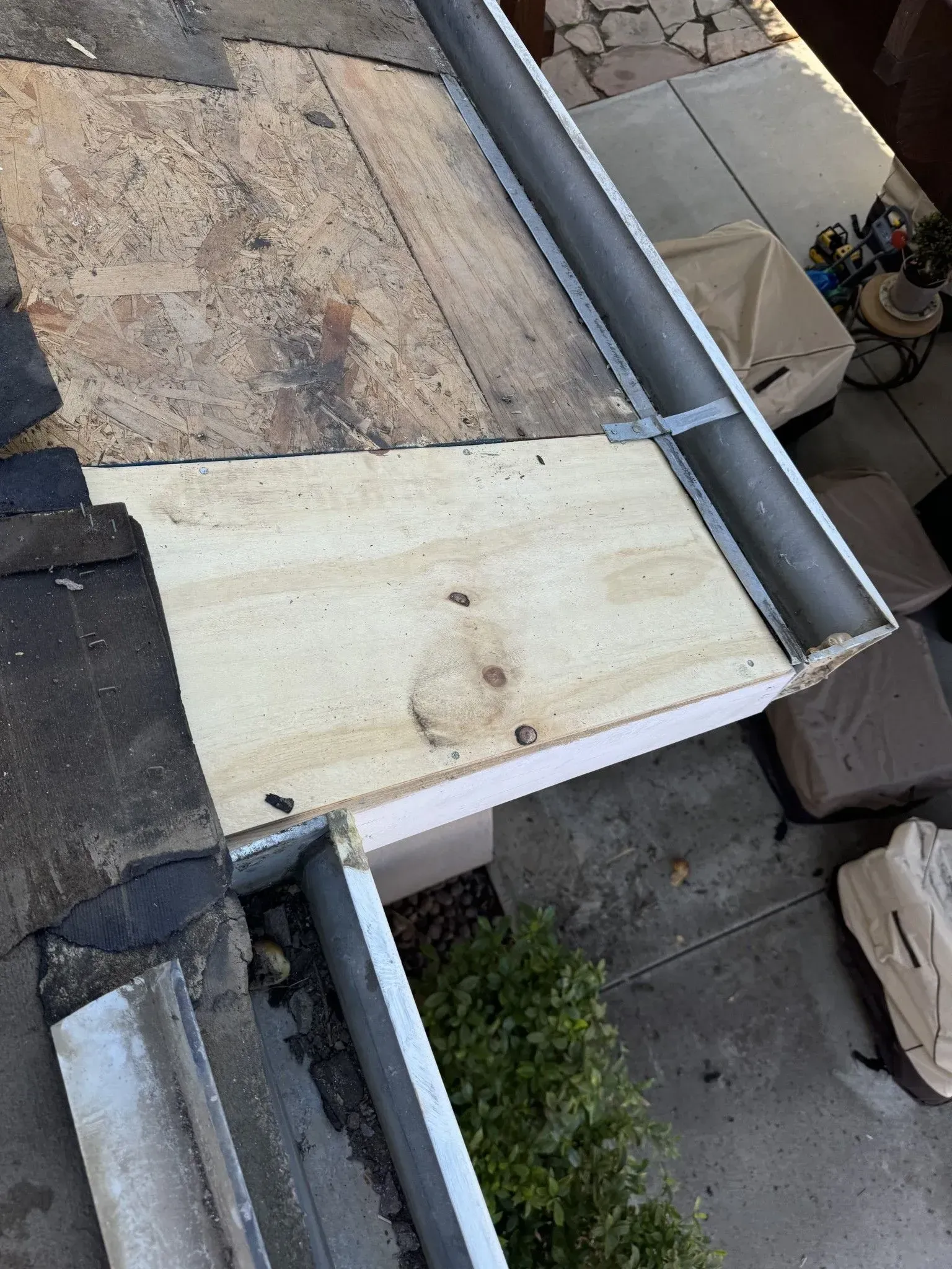 A roof with a gutter and a piece of wood on it.