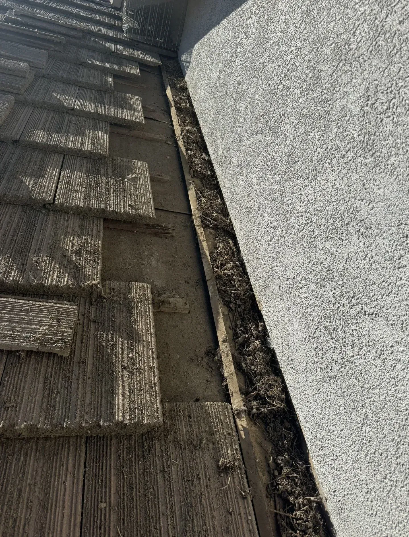 A close up of a gutter on a roof next to a wall.