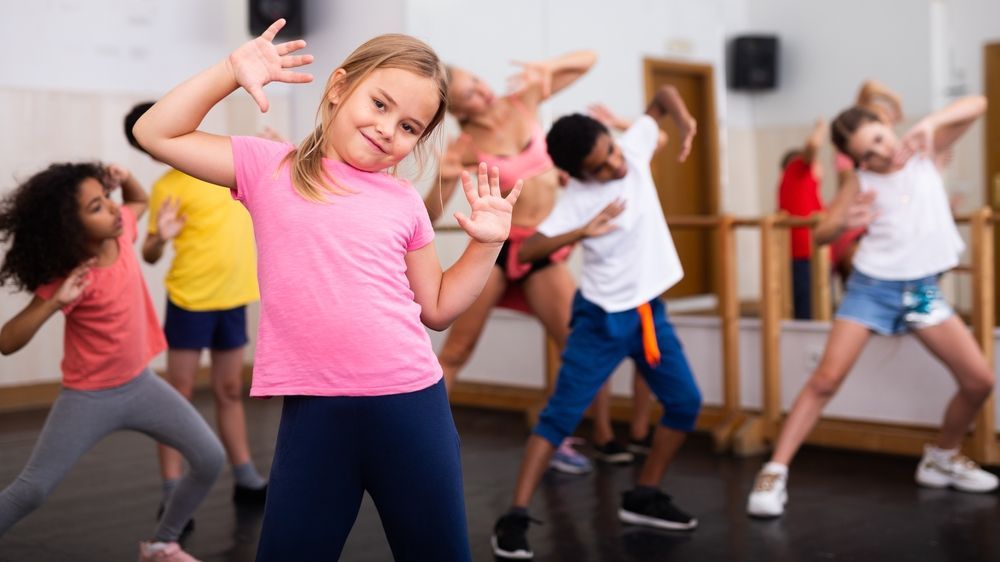 A group of children are dancing in a dance studio.