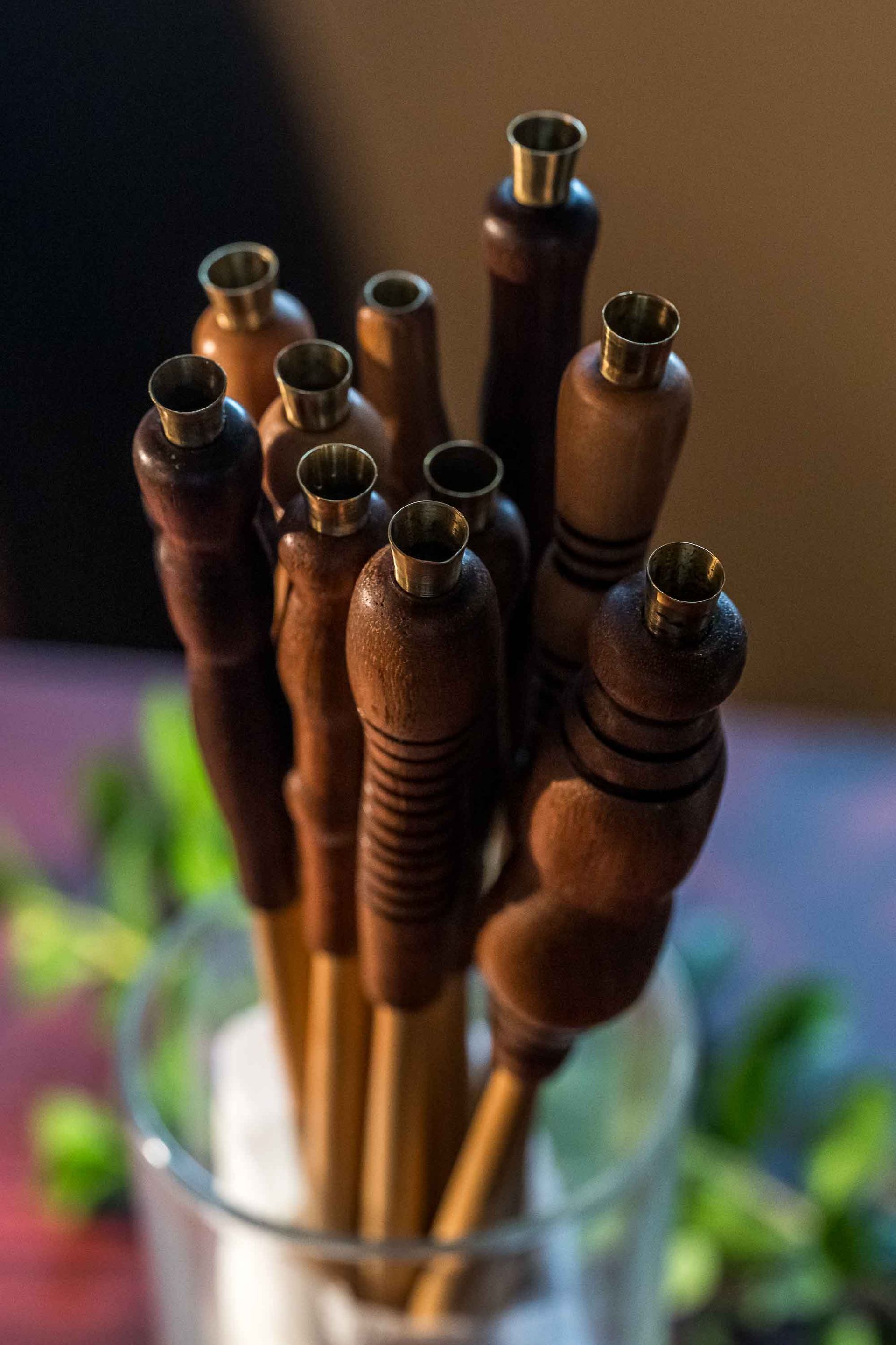 A bunch of wooden sticks are in a glass on a table.