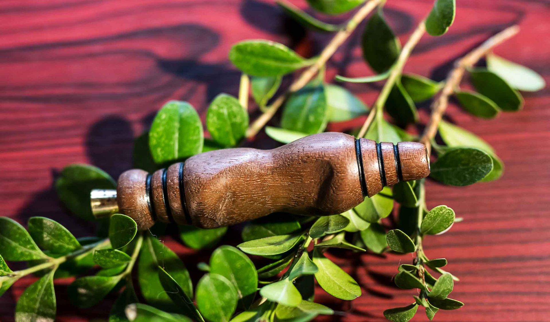 A wooden object is surrounded by green leaves on a wooden table.