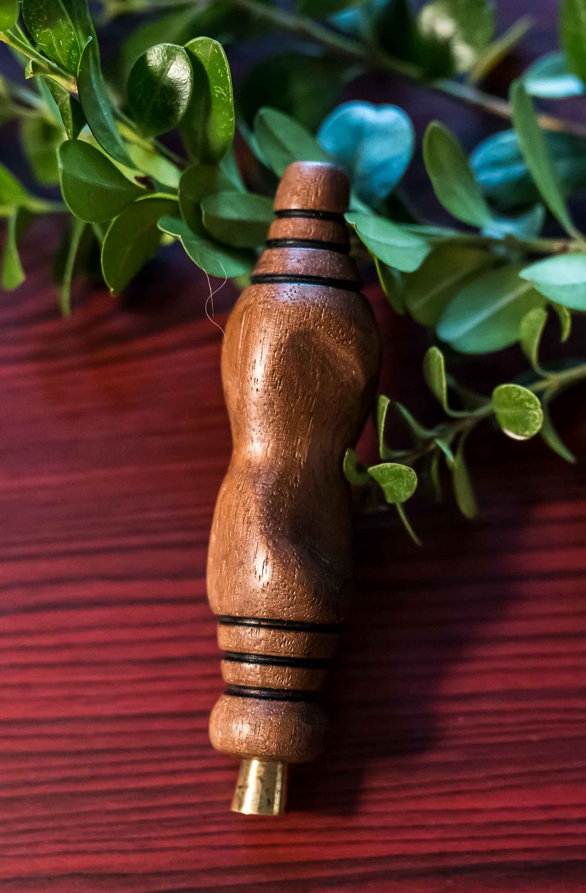 A wooden object is sitting on a wooden table next to a plant.