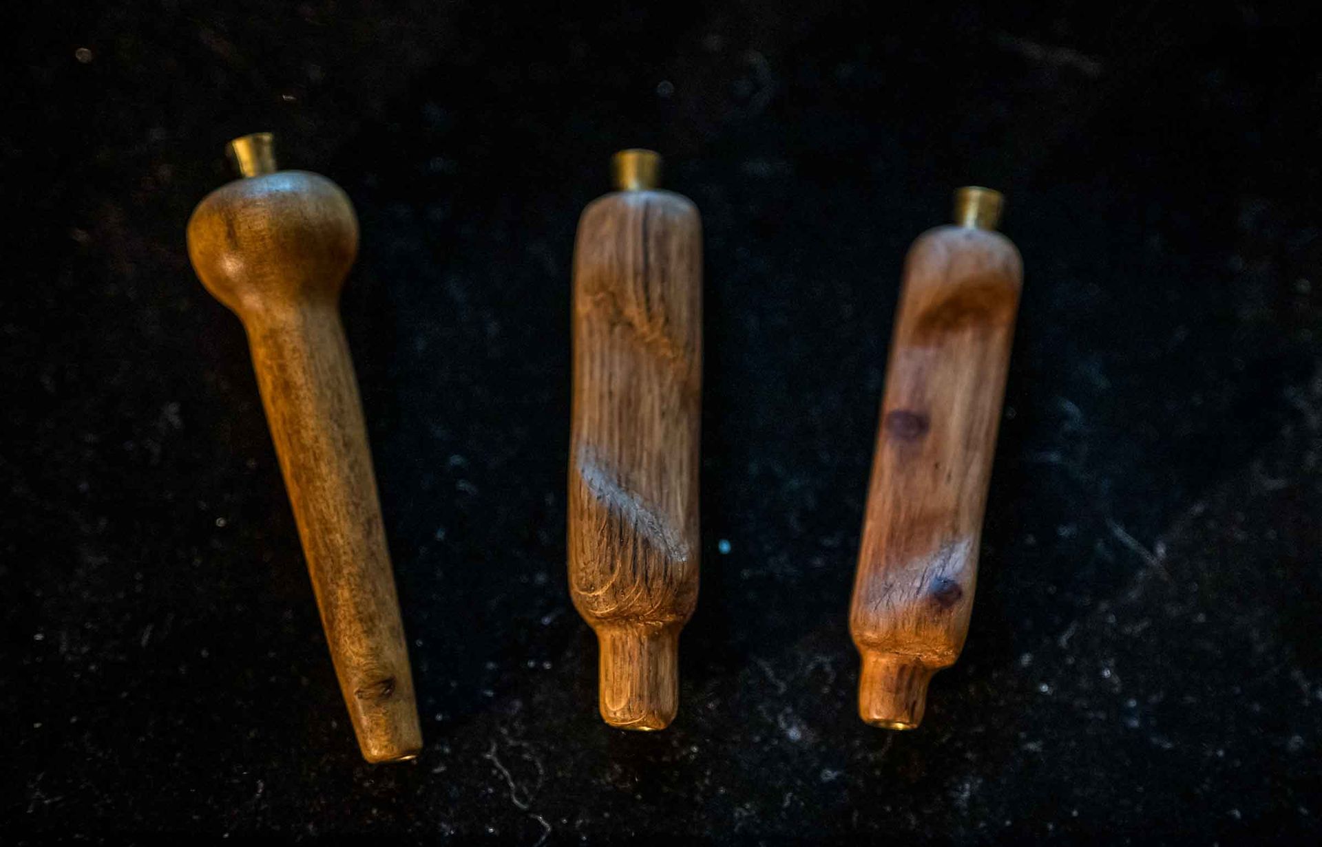 Four wooden handles are sitting on a black surface.