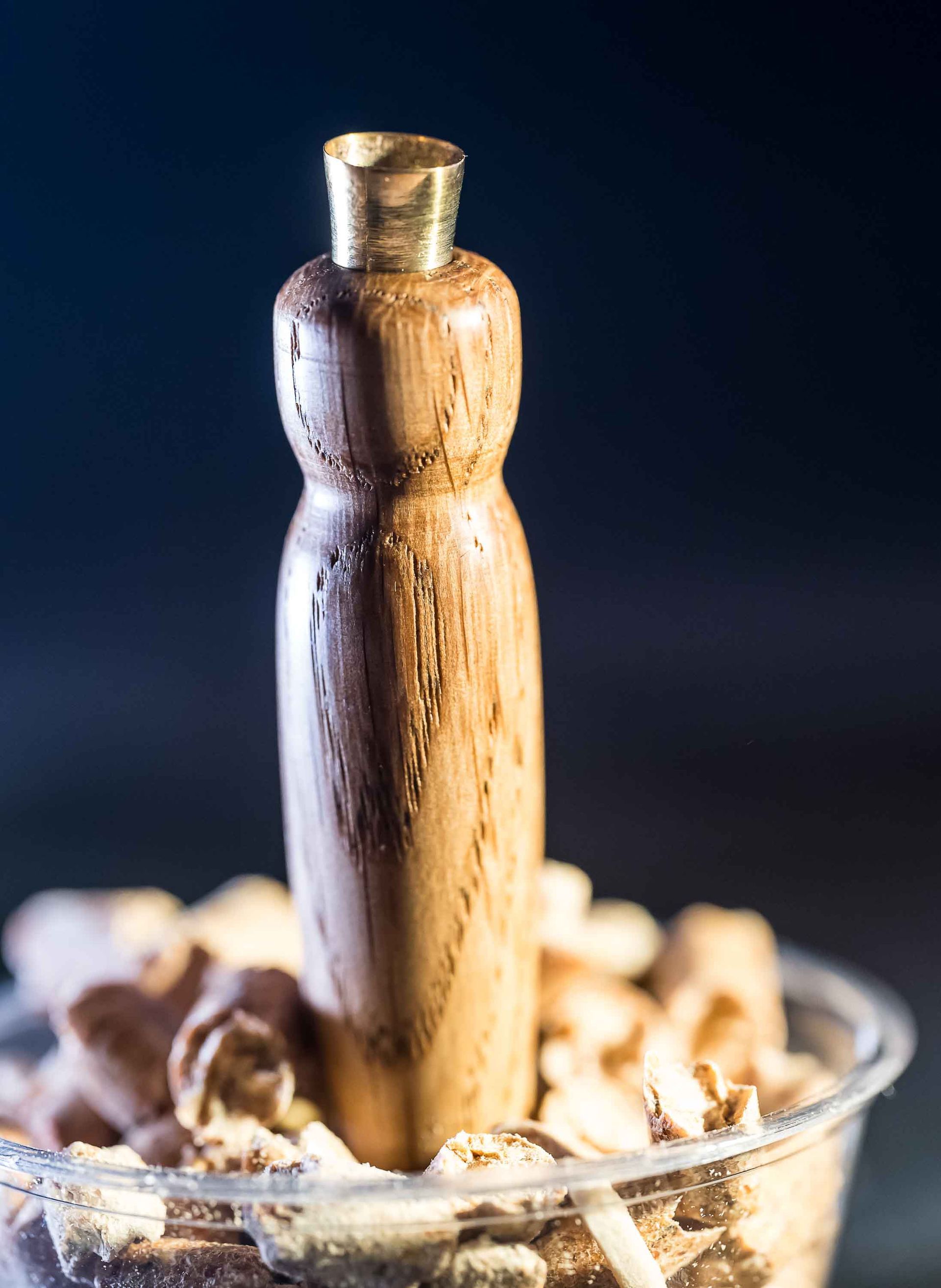 A wooden bottle is sitting on top of a bowl of wood chips.
