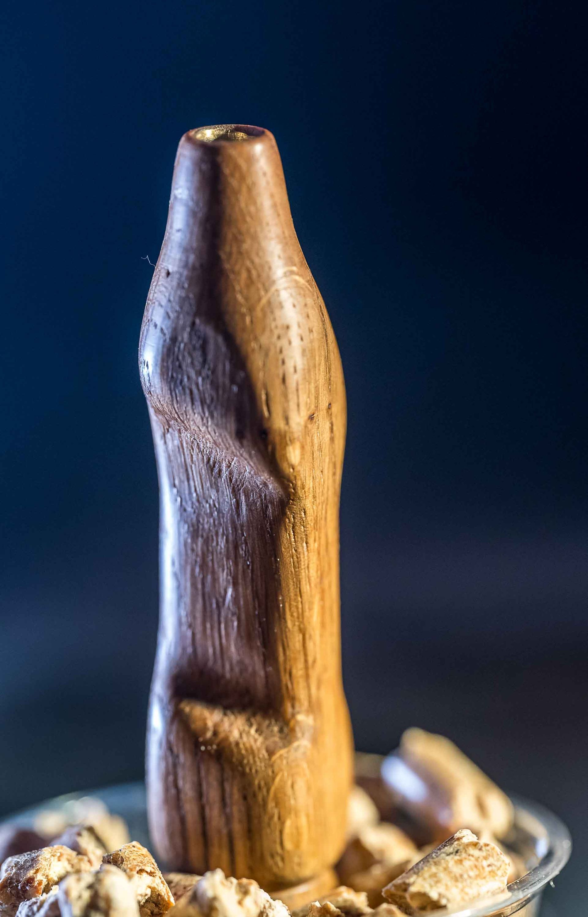 A wooden bottle is sitting on top of a pile of nuts.