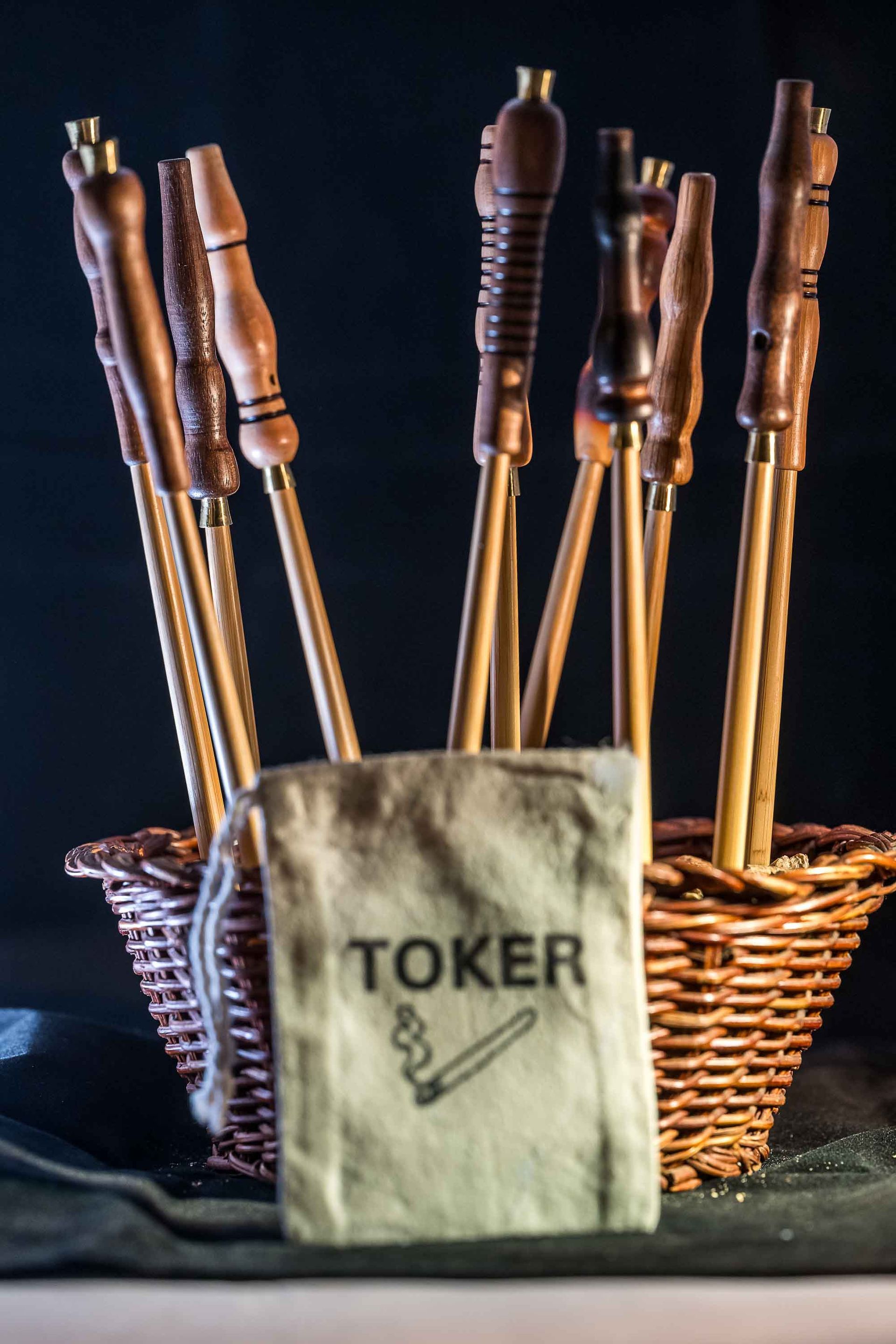 A wicker basket filled with wooden sticks and a toker bag