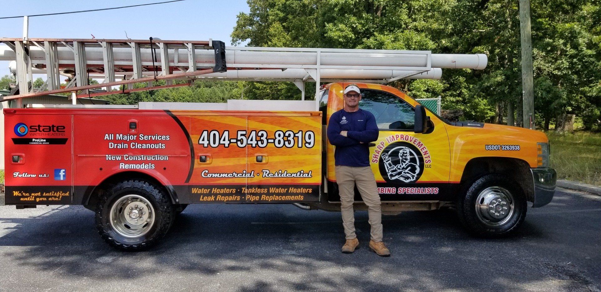 A man is standing in front of a yellow and red truck.