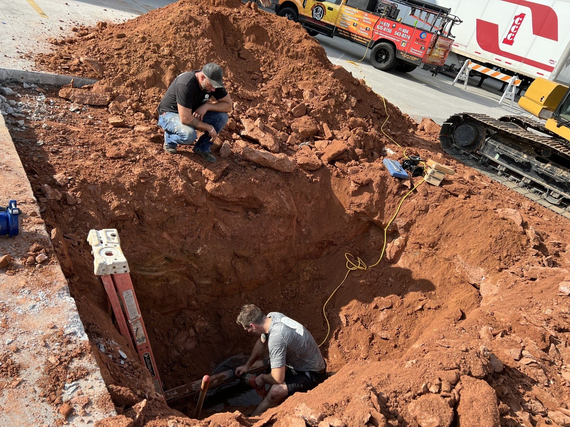 Two men are working in a hole in the ground.