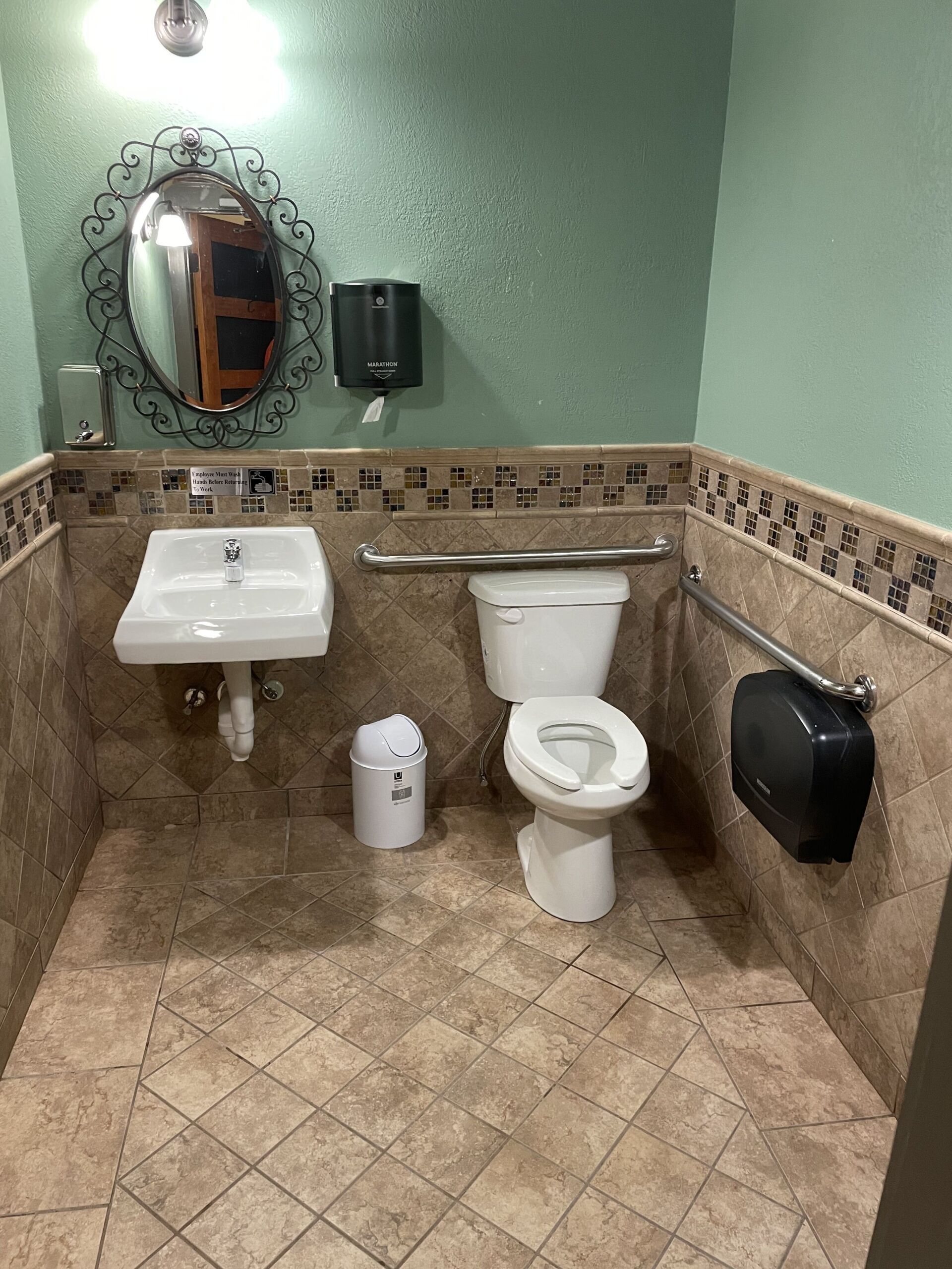 A bathroom with a toilet , sink and mirror.