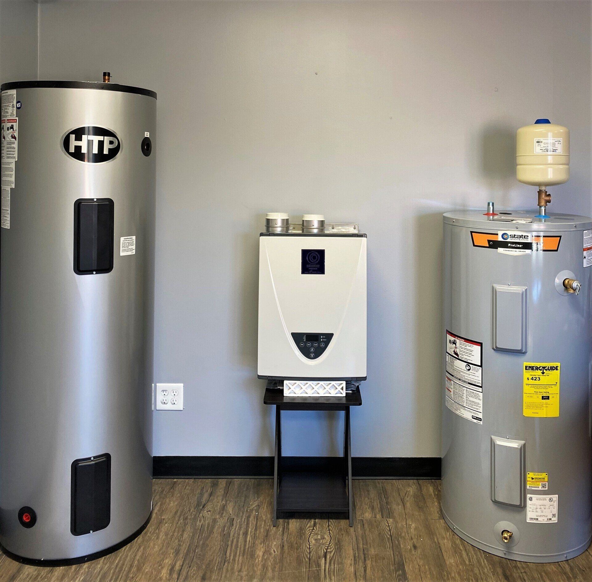 Three water heaters are sitting next to each other in a room.