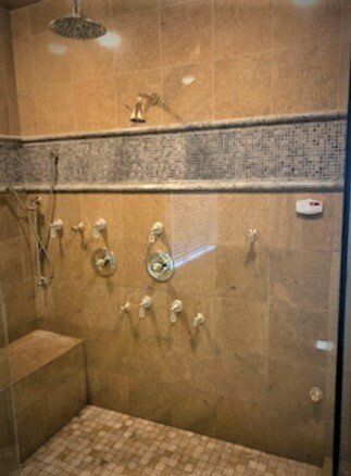 A walk in shower with a glass door and a shower head.