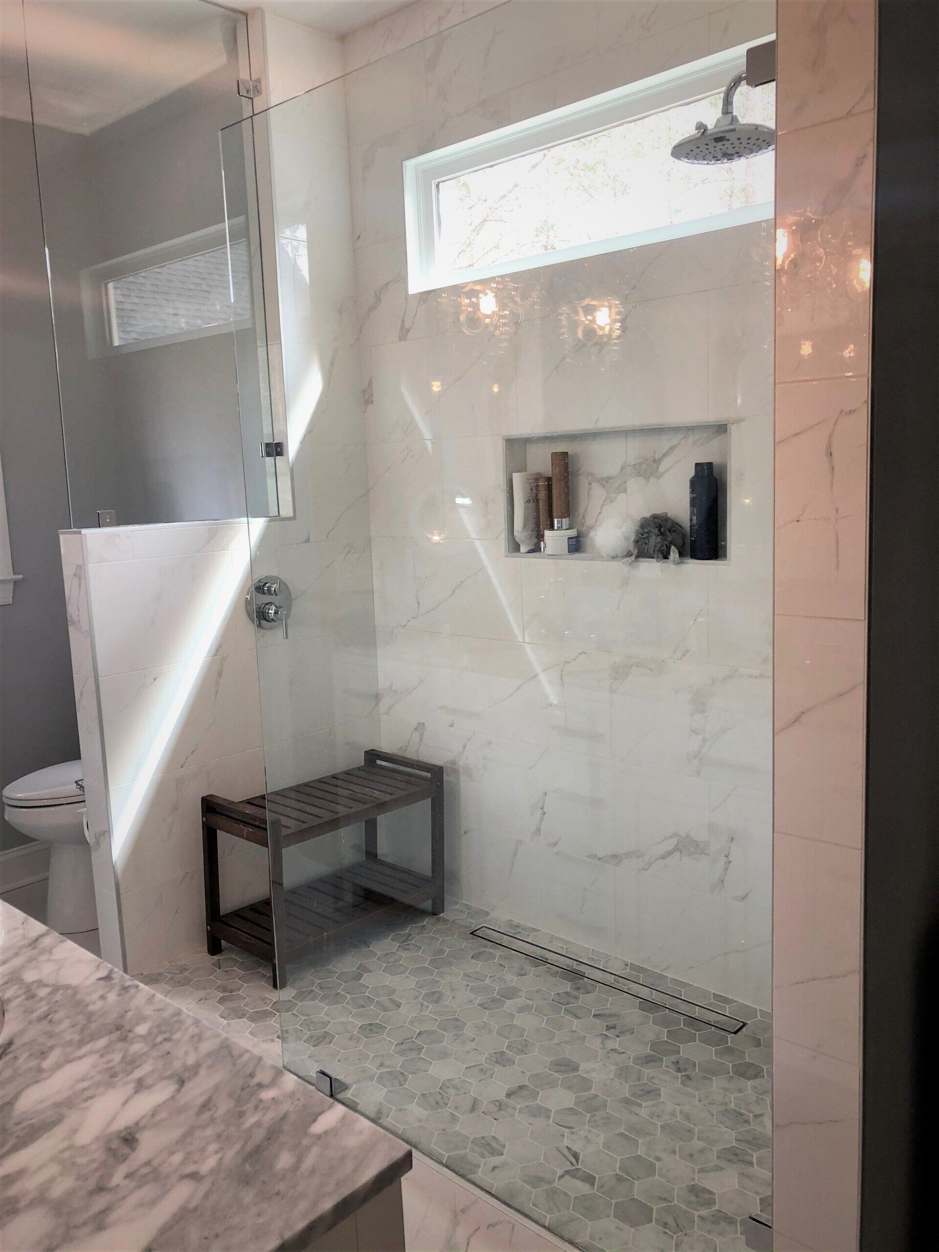 A bathroom with a walk in shower and a bench.
