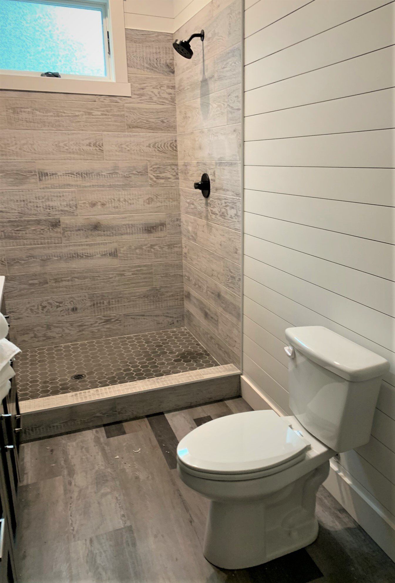 A bathroom with a toilet , sink and shower.