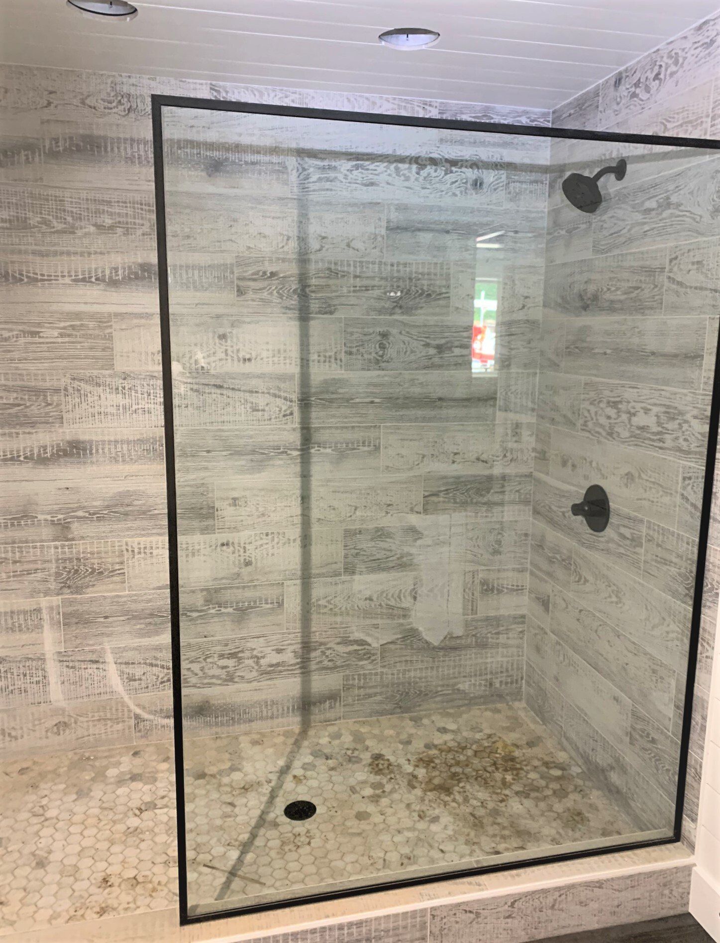 A bathroom with a walk in shower with a black frame.