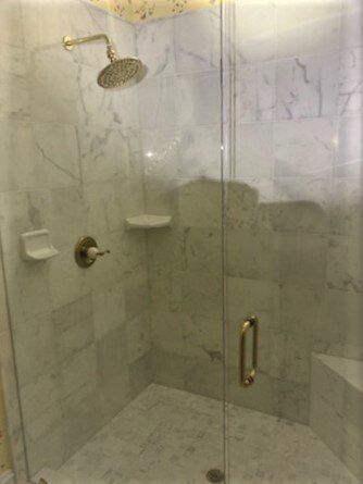 A shower stall with a glass door and a shower head.