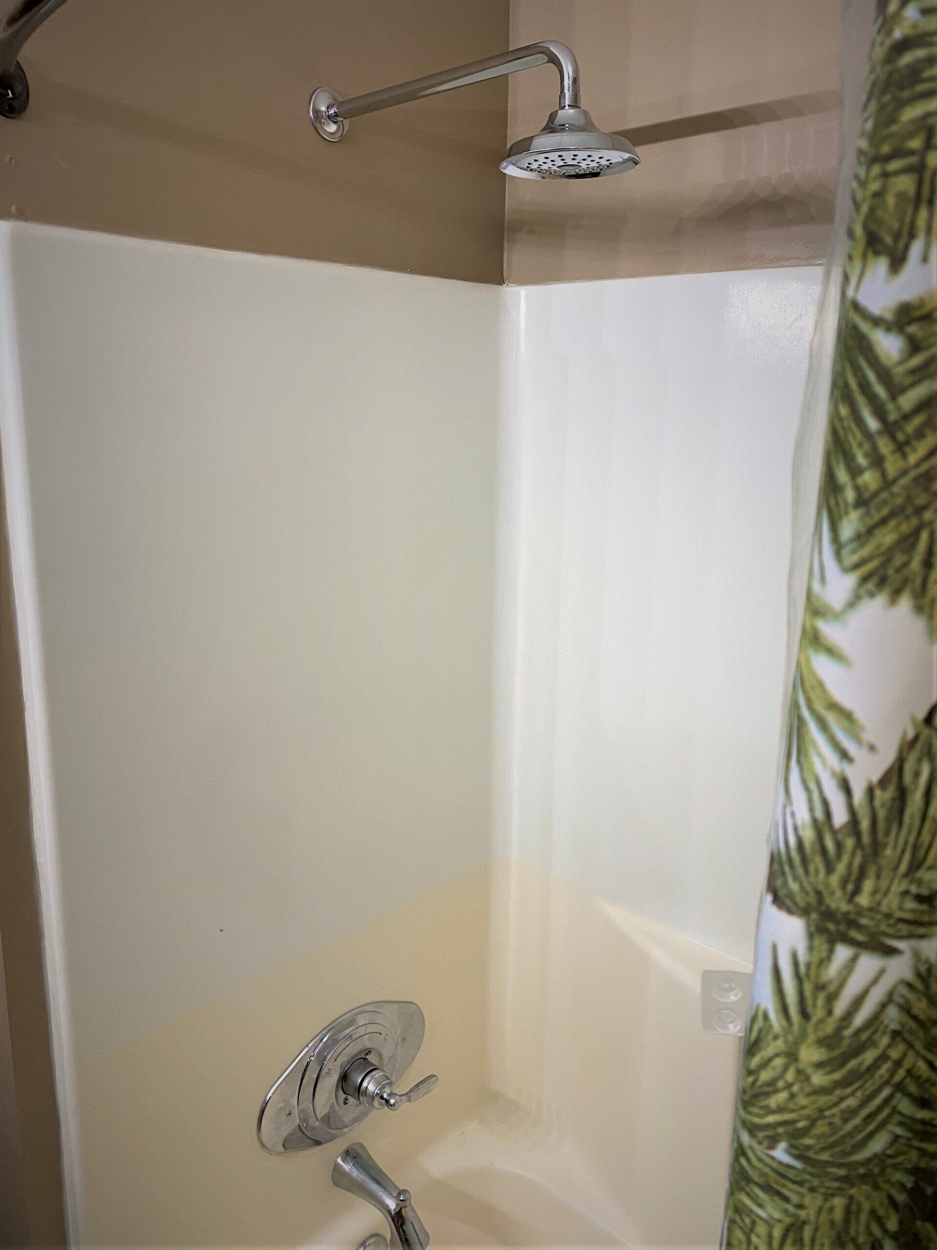 There is a shower with a shower head and a shower curtain.