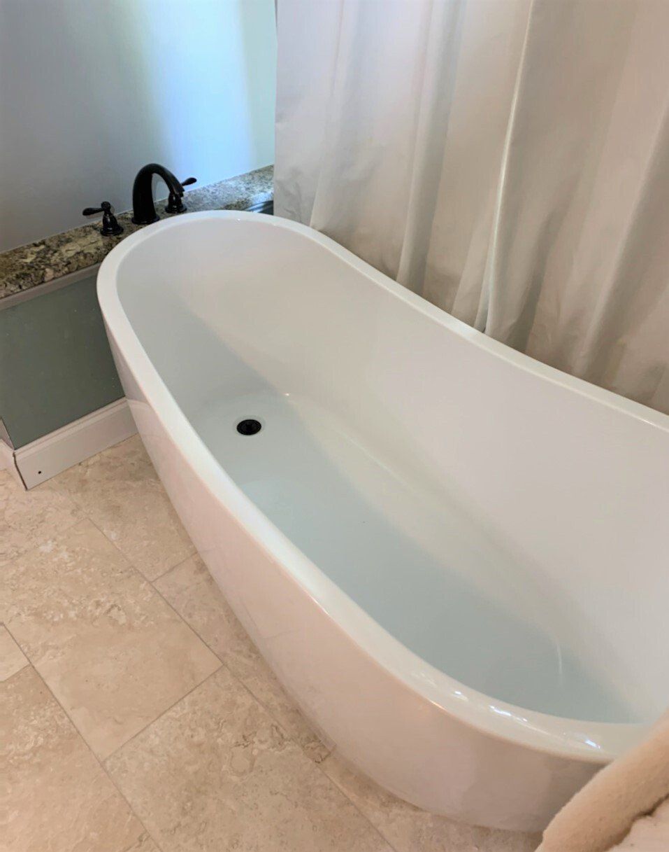 A white bathtub is sitting in a bathroom next to a shower curtain.