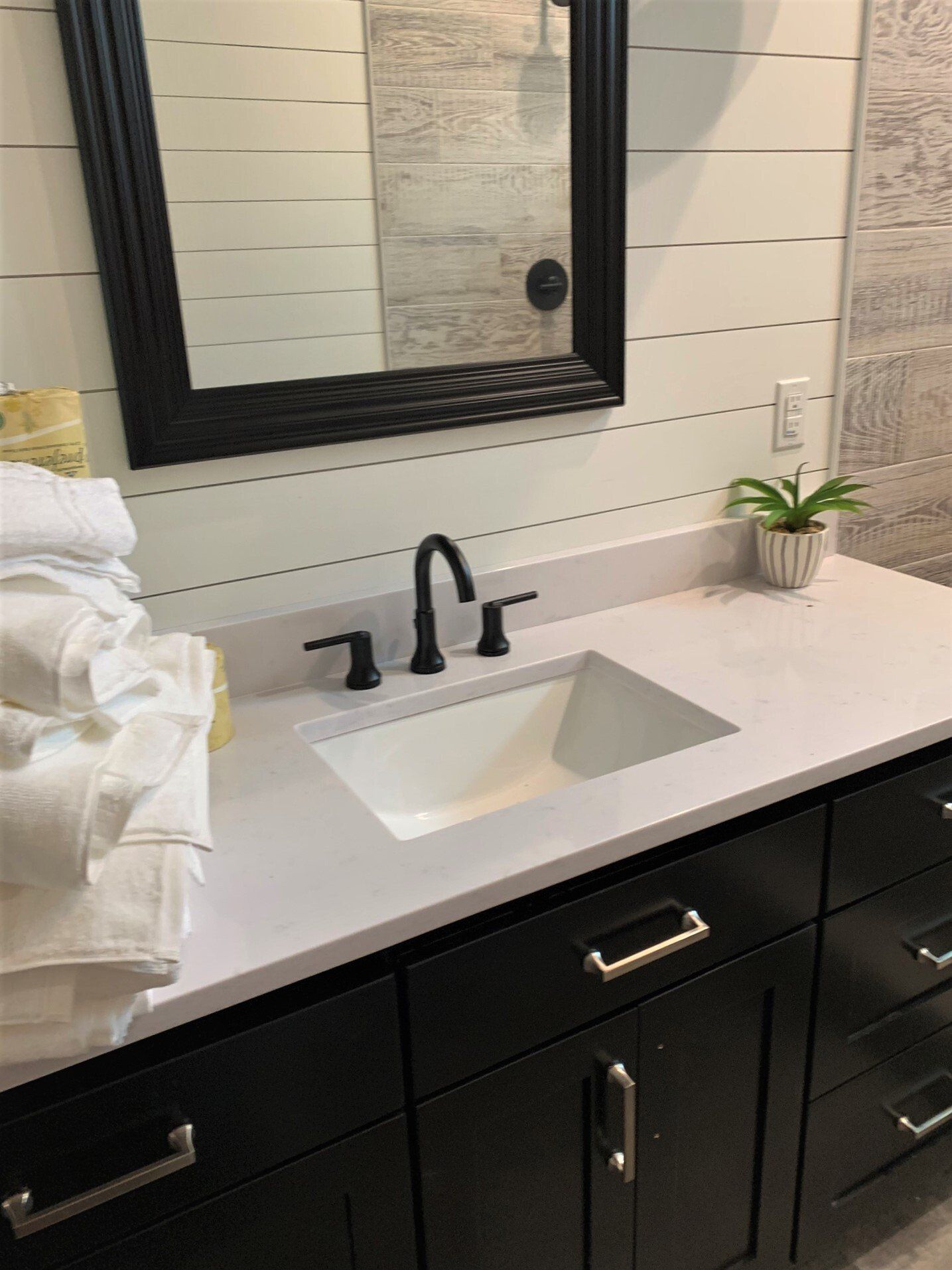 A bathroom with a sink , mirror and towels on the counter.