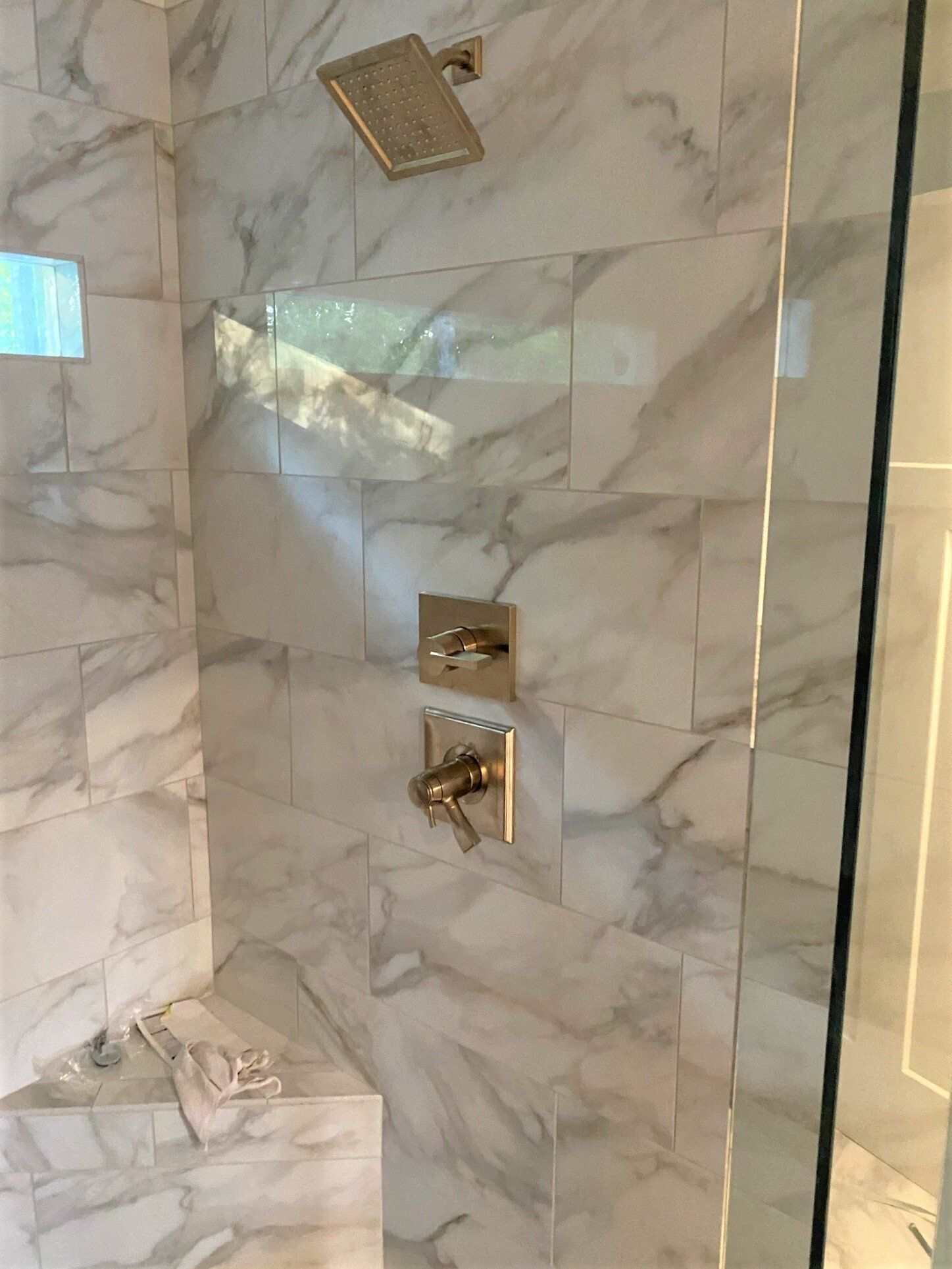 A bathroom with marble tiles and a walk in shower.