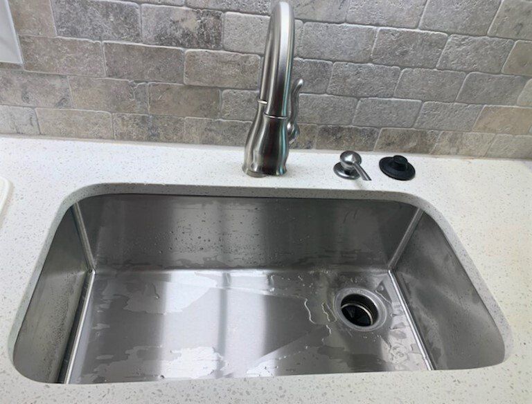 A stainless steel kitchen sink with a faucet on top of it.