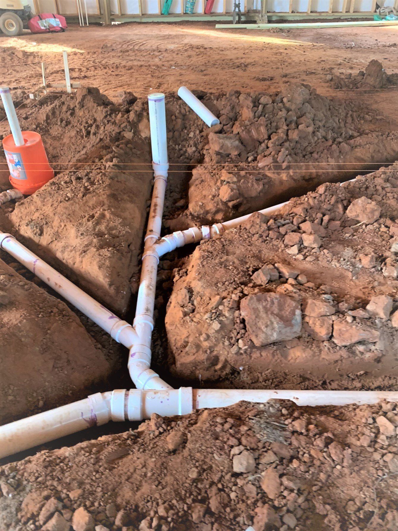 A bunch of pipes are laying in the dirt.